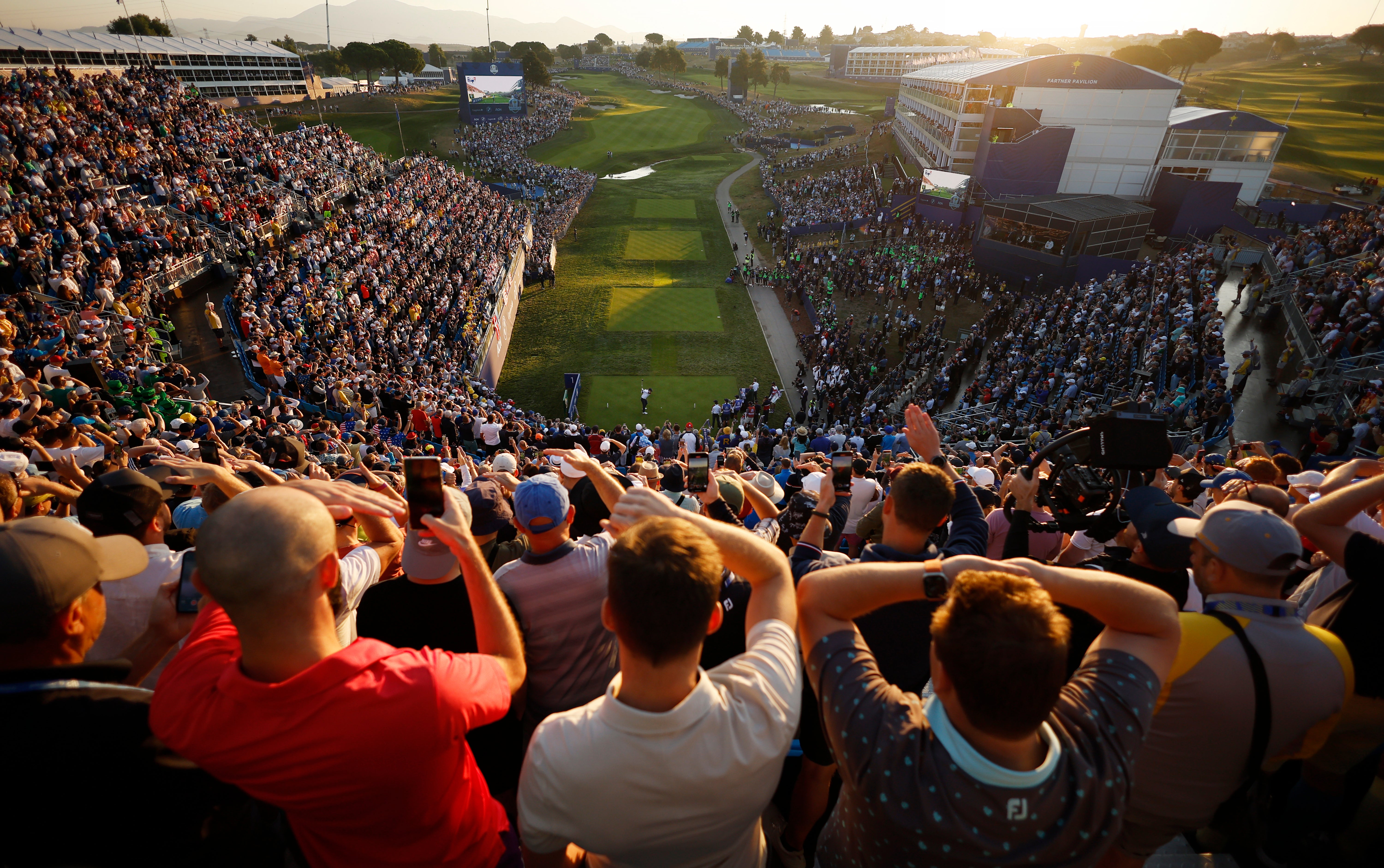 Fans shield their eyes as McIlroy drives on the first tee