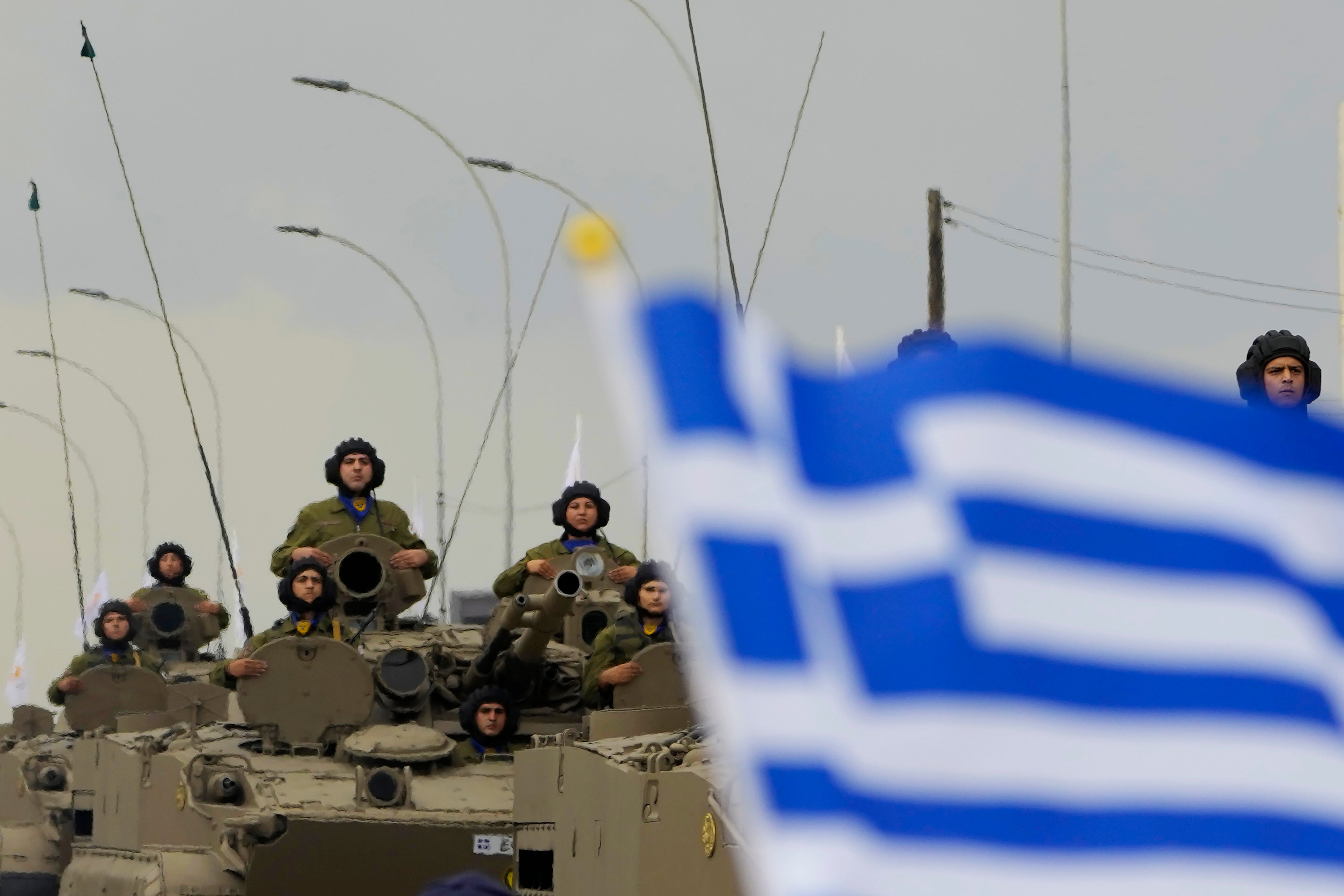 Cyprus’ soldiers on the military vehicles pass behind a Greek flag during a military parade marking the 63th anniversary