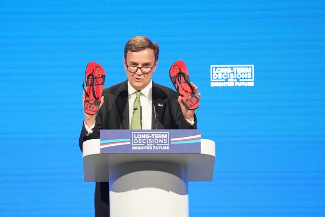 <p>Chairman of the Conservative Party Greg Hands holds up a pair of Labour leader Sir Keir Starmer ‘flip flops’ (PA)</p>