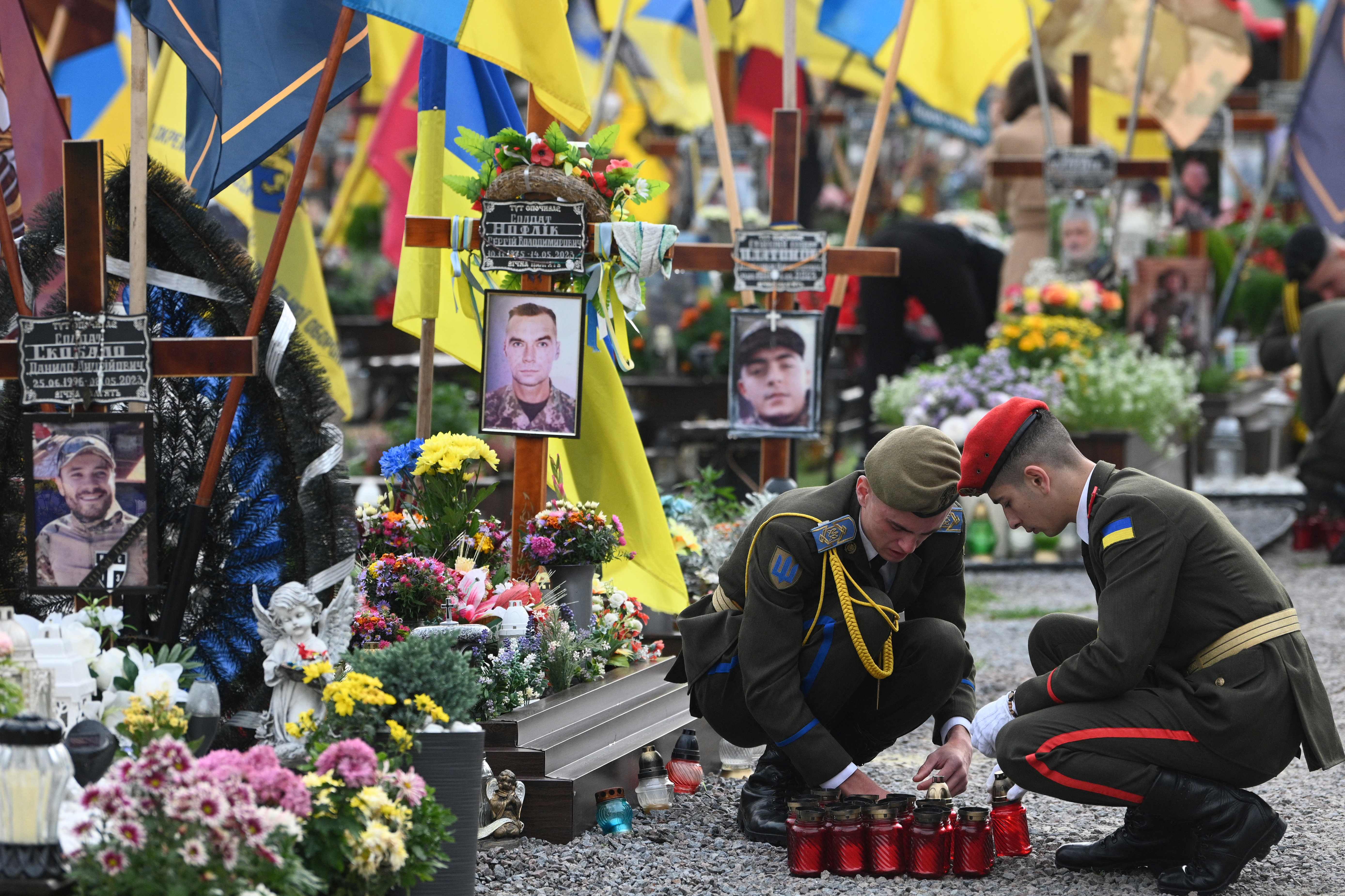 Cadets light candles as they pay tribute to fallen Ukrainian soldiers at the Lychakiv Cemetery to mark Defenders Day of Ukraine in Lviv