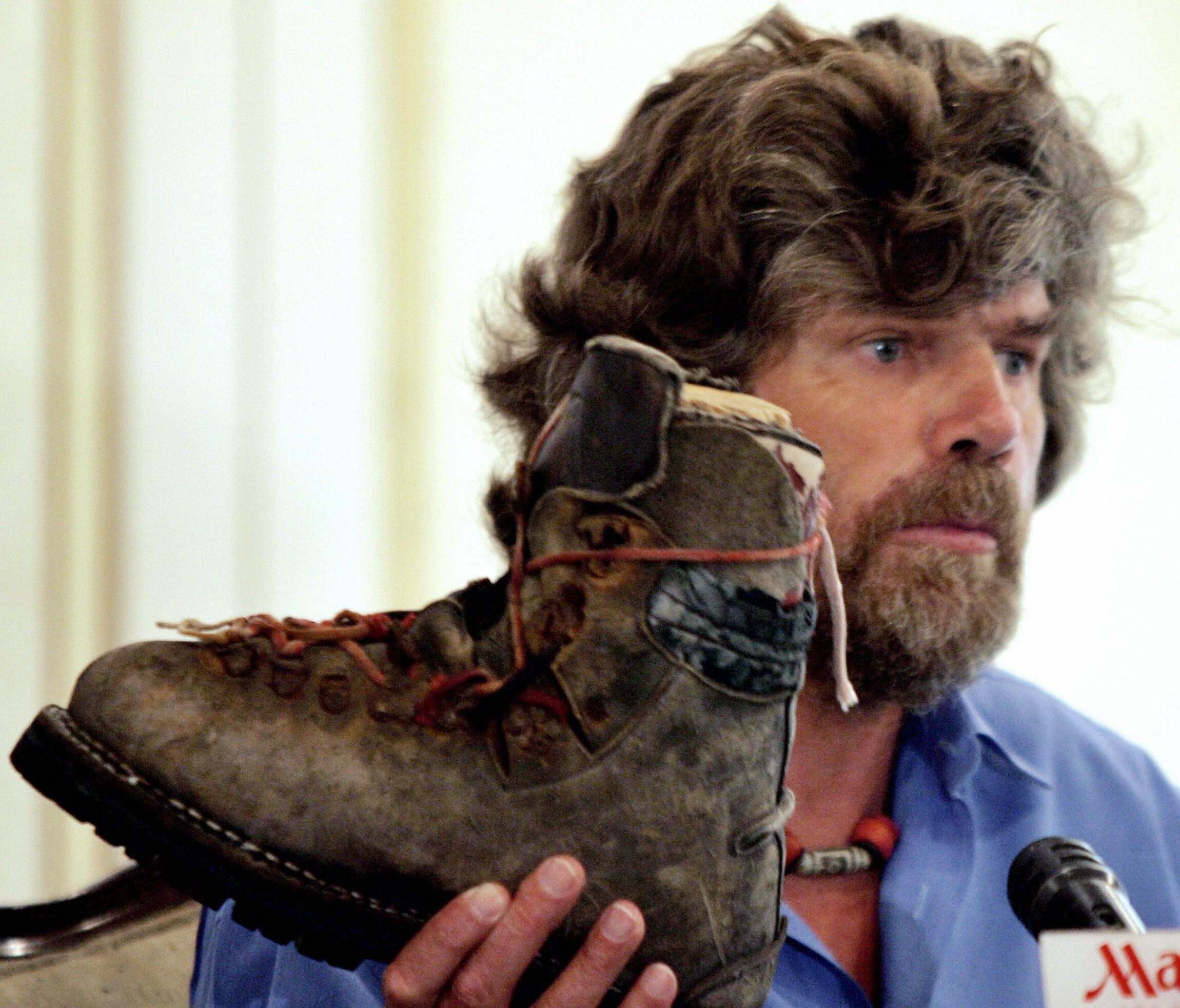 Messner shows a shoe, allegedly part of his brother’s equipment, to media representatives during a press conference in Islamabad in 2005