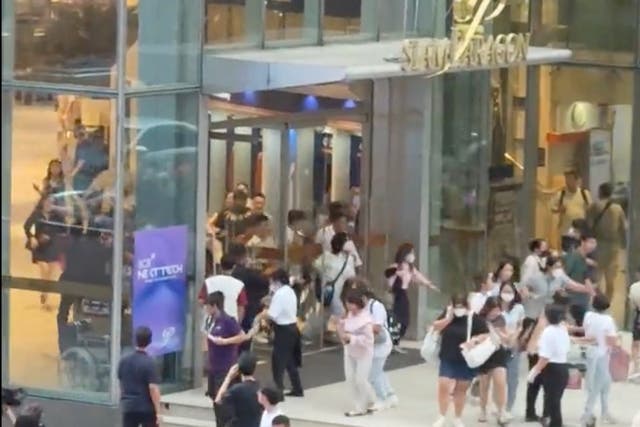 <p>Shoppers stream out of the Siam Paragon mall in central Bangkok amid reports of shots fired inside</p>