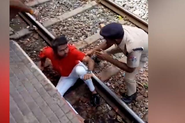 <p>The man is helped up after surviving falling under a moving train in India </p>