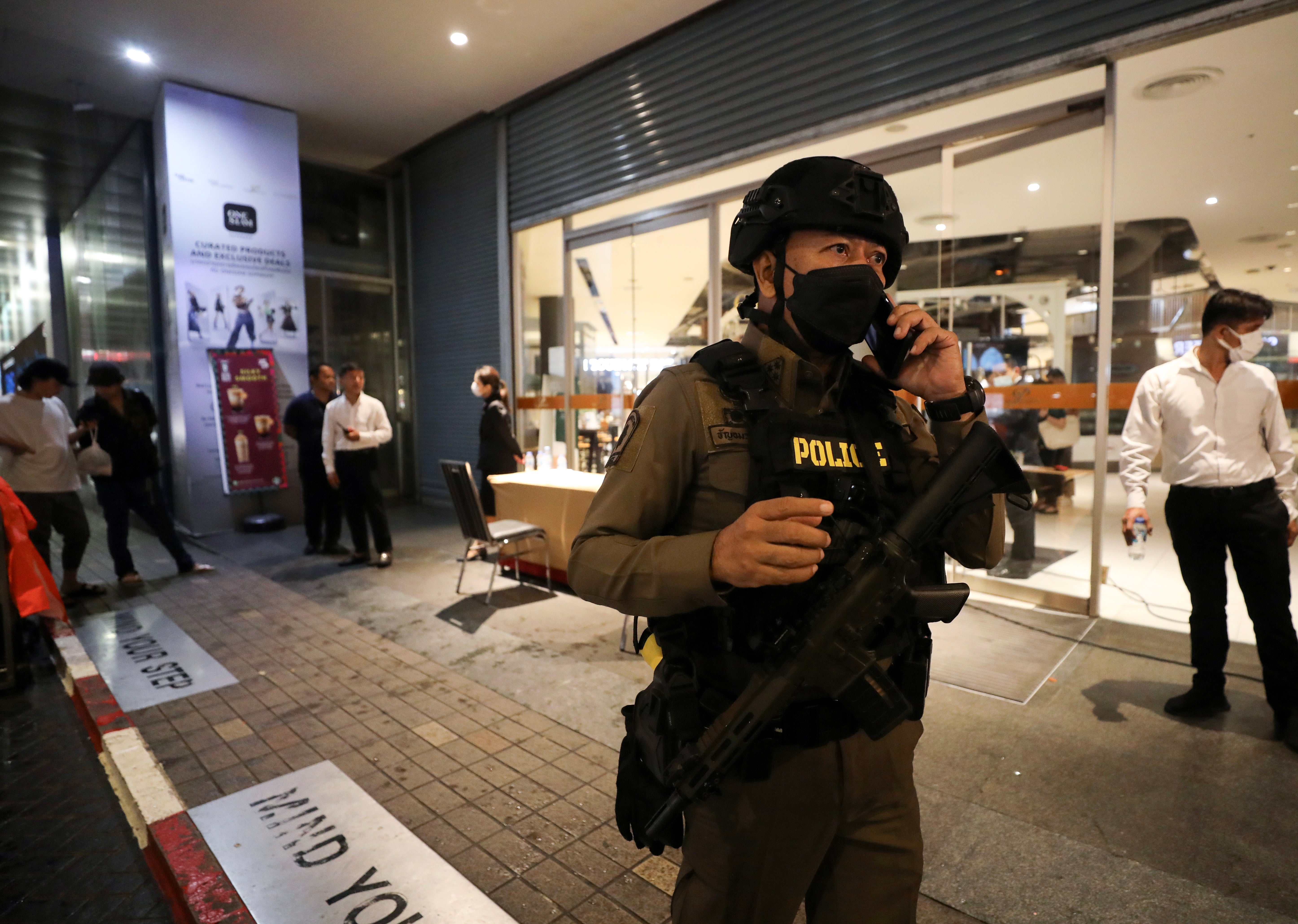 An armed police officer speaks on a mobile phone as he leaves the Siam Paragon shopping mall