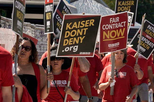 <p>Kaiser Permanente mental health workers and supporters march outside a Kaiser facility in California </p>