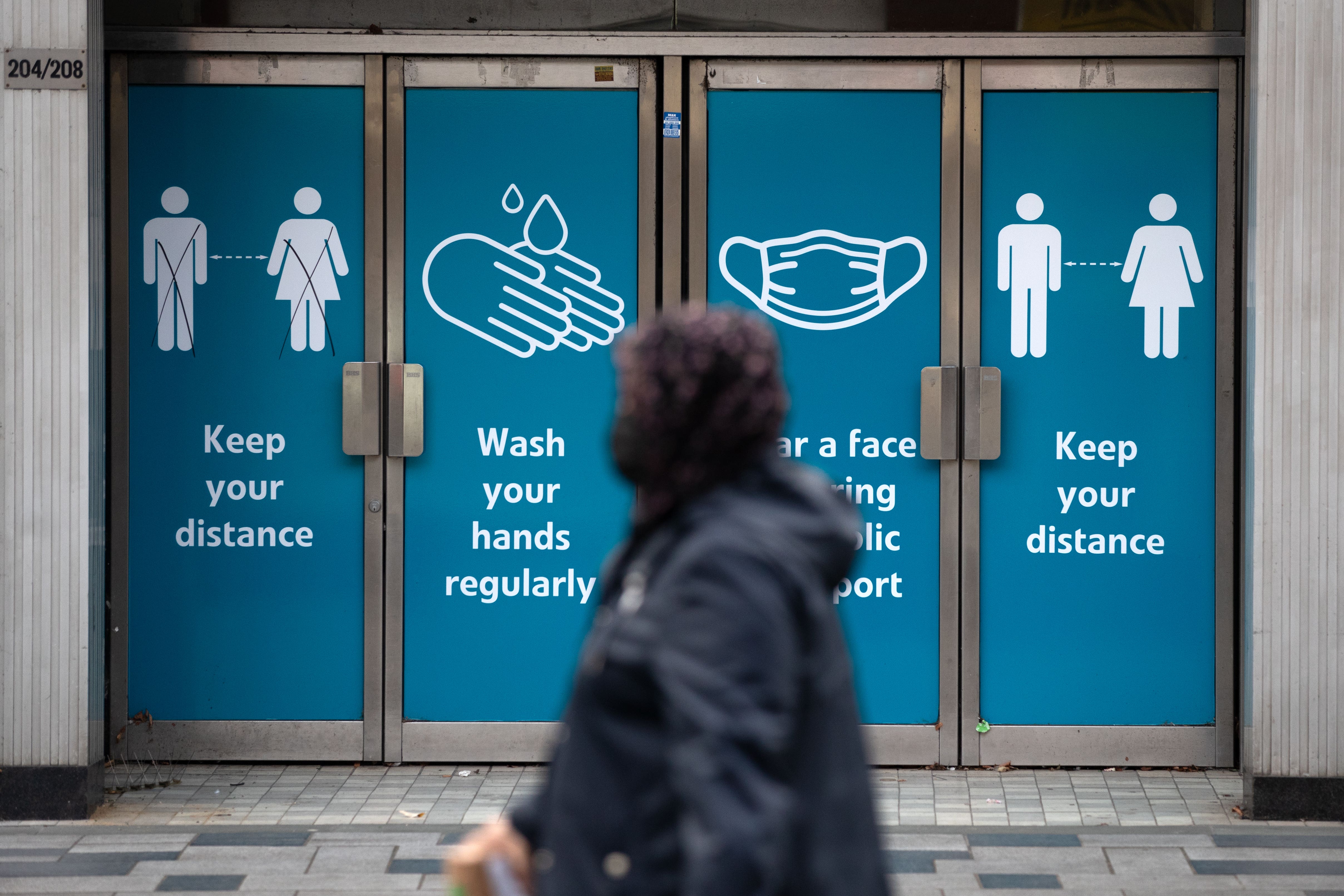 A person passes social distancing signs in 2020 (Andrew Matthews/PA)