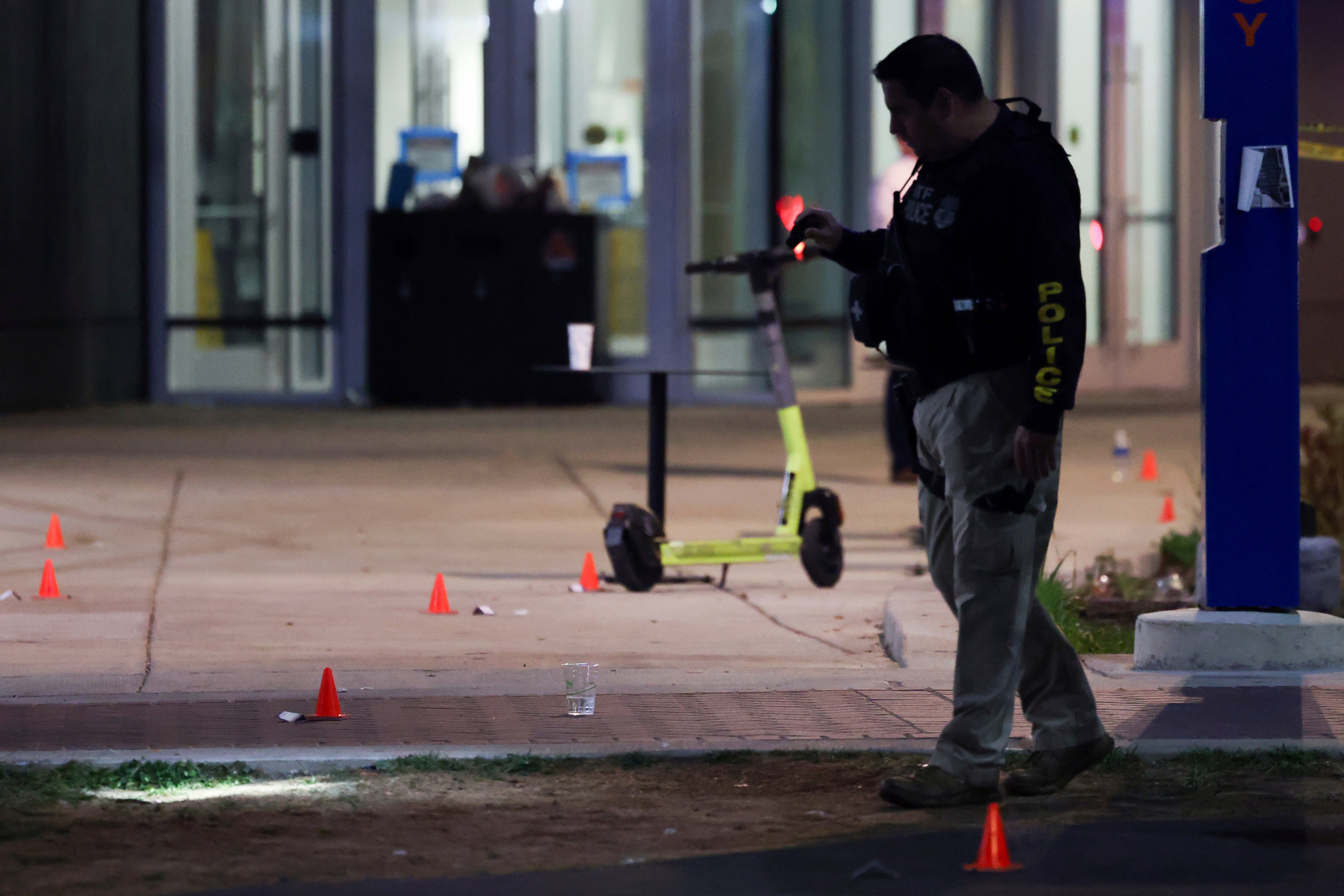 A police officer searches for evidence in front of a building at Morgan State Universit