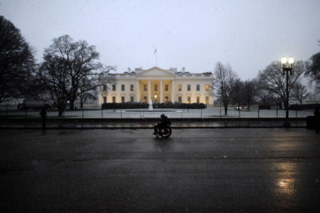 <p>A man in a wheelchair passes by the White House under snowfall in Washington, DC</p>