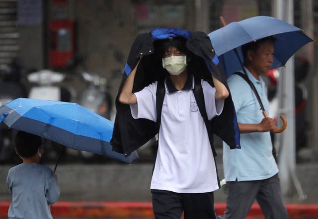 <p>People walk in the rain in Taipei as Typhoon Koinu batters the island with record wind gusts  </p>