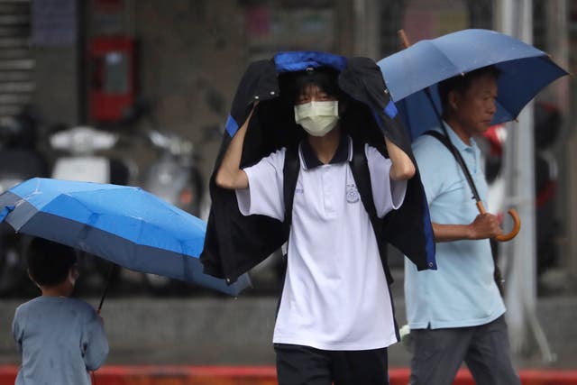 <p>People walk in the rain in Taipei as Typhoon Koinu batters the island with record wind gusts  </p>