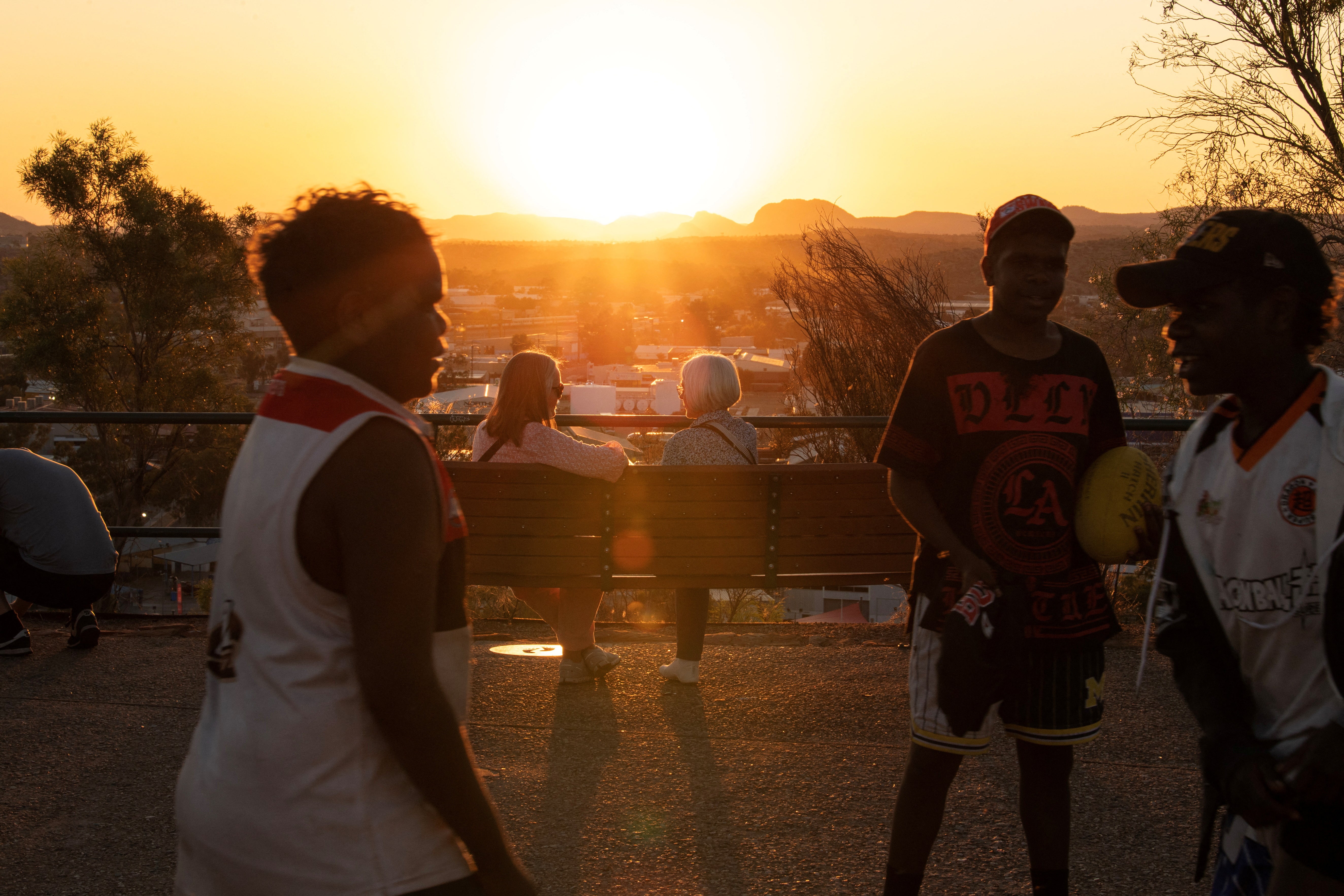 Boys play as people watch the sunset over Alice Springs