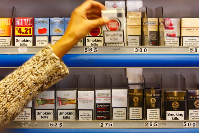 A shop assistant in Portsmouth reaches for a packet of cigarettes (Chris Ison/PA)