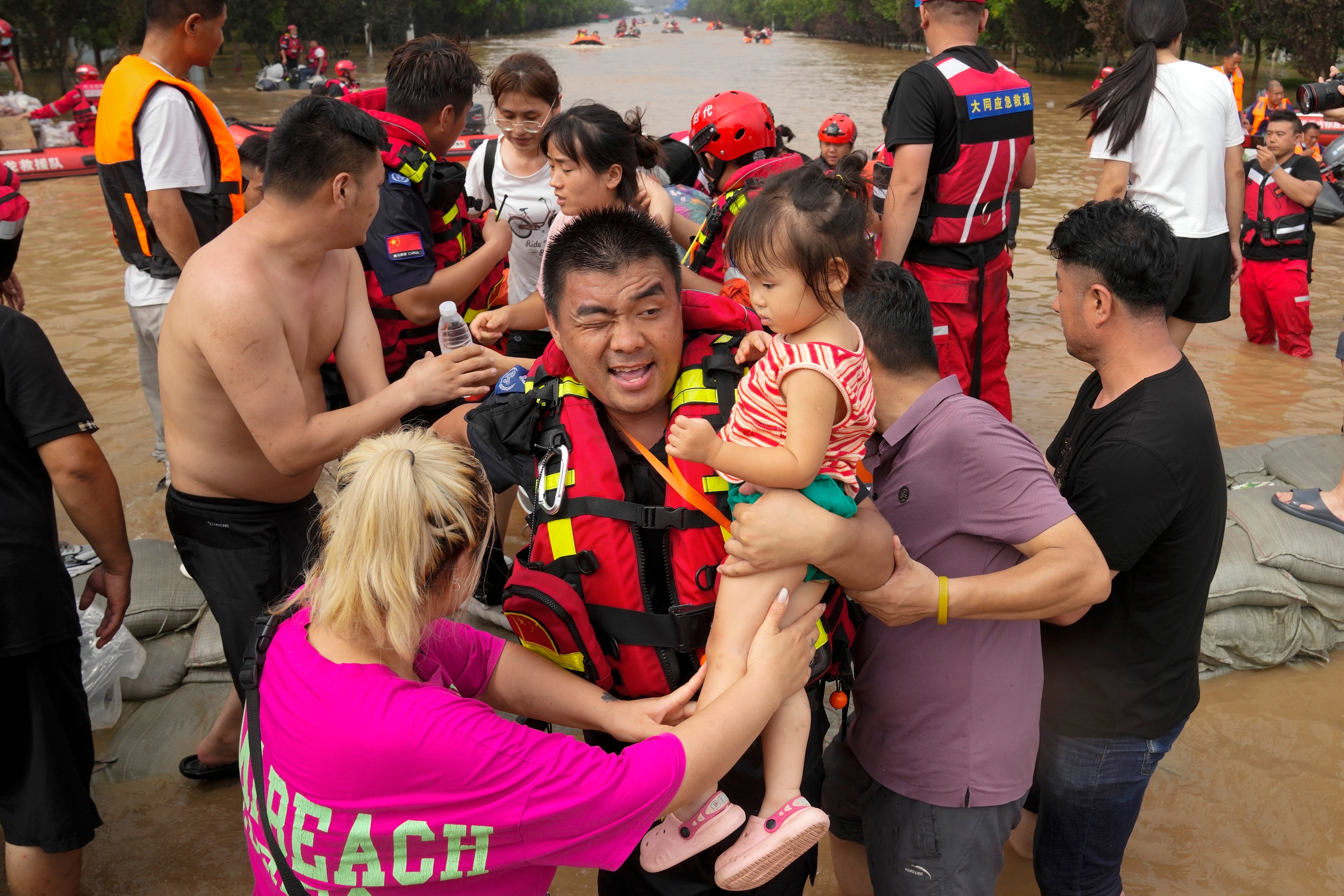 Rescuers using rubber boats to evacuate children through floodwaters in Zhuozhou in northern China's Hebei province in August