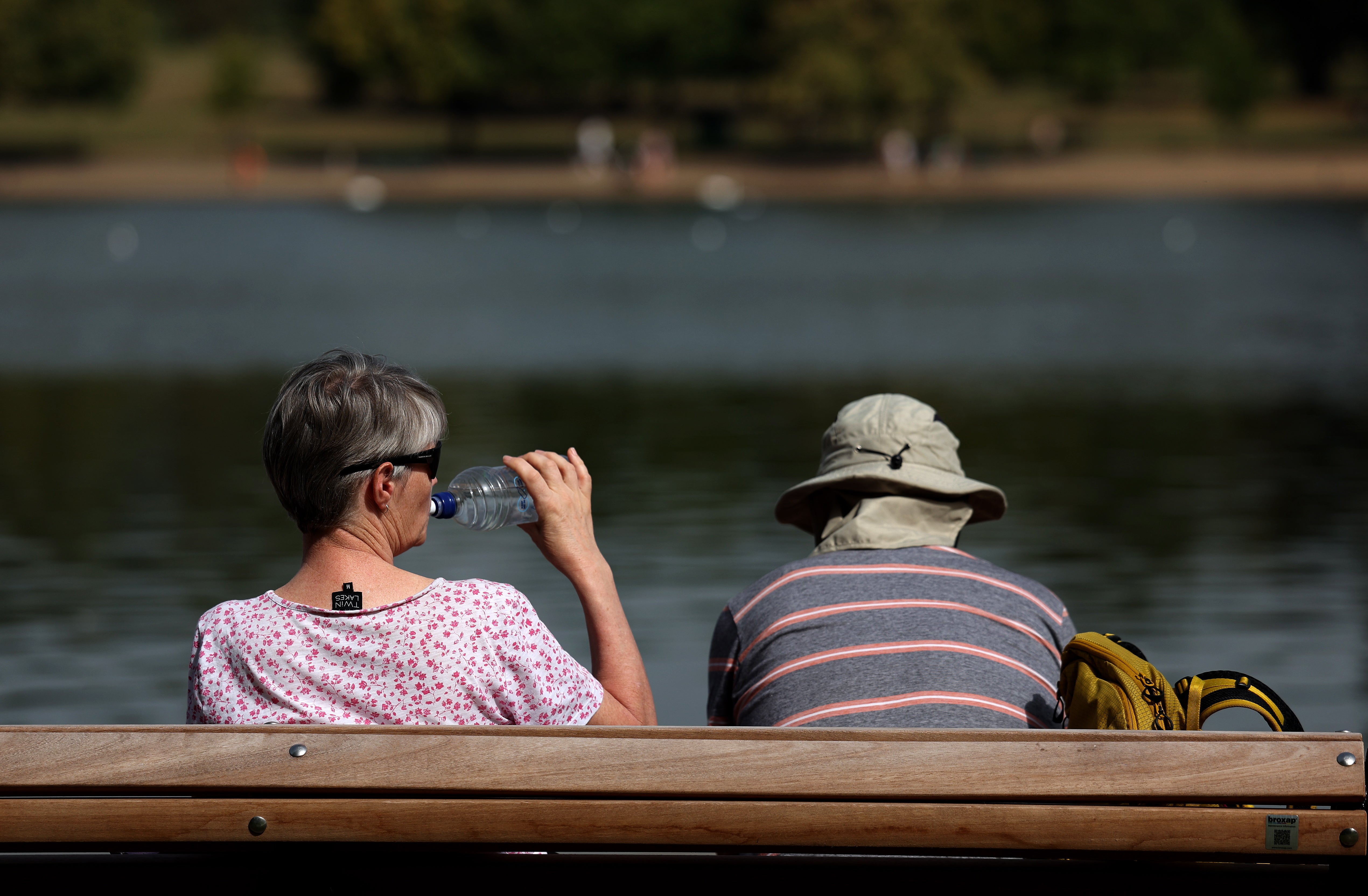 A couple sit on a bench during a heatwave at the Serpentine Lake at Hyde Park in London