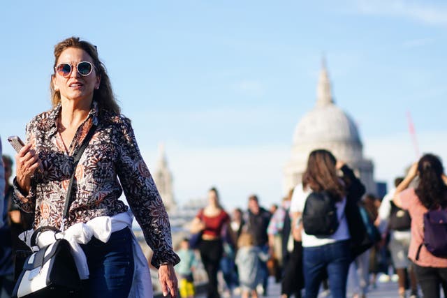 People enjoy the sunshine as they walk across Millennium Bridge in London. (Victoria Jones/PA)
