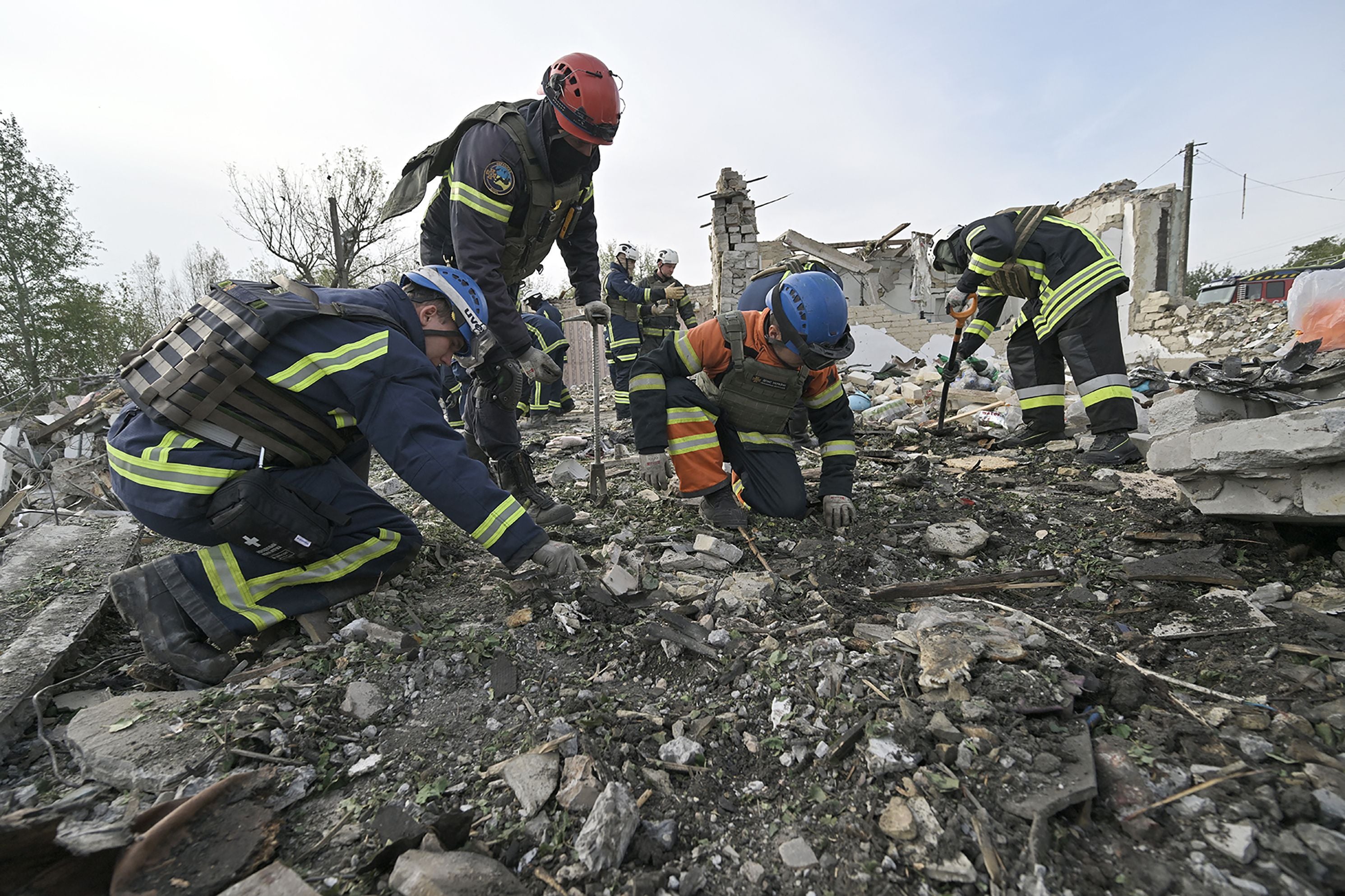 Ukrainian emergency personnel clear debris on the site of a Russian strike which hit a shop and cafe in the village of Groza, some 30 kilometres west of Kupiansk, on October 6, 2023, amid the Russian invasion of Ukraine