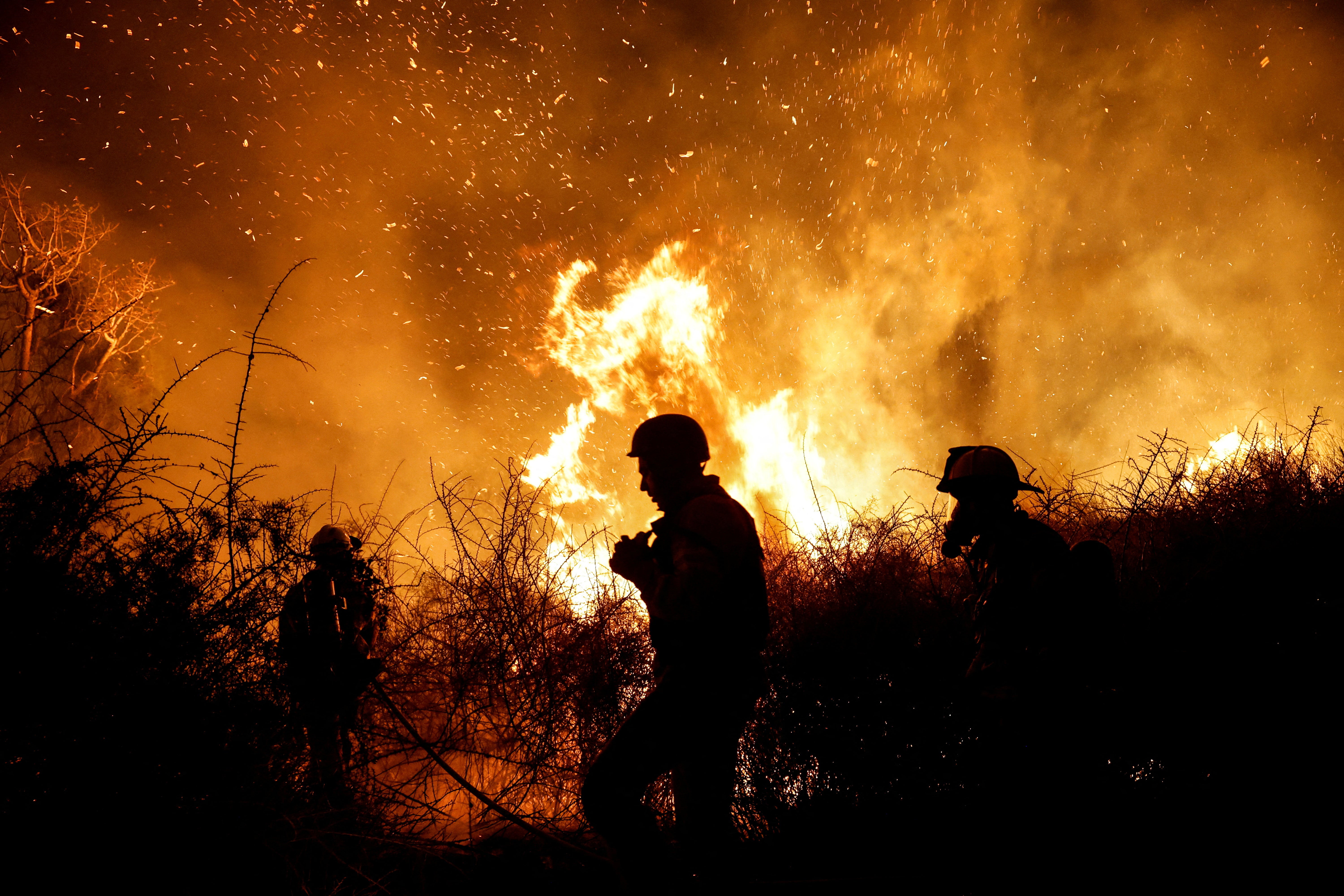 Firefighters work to put out a fire in an open field, following a mass-infiltration by Hamas gunmen from the Gaza Strip in southern Israel