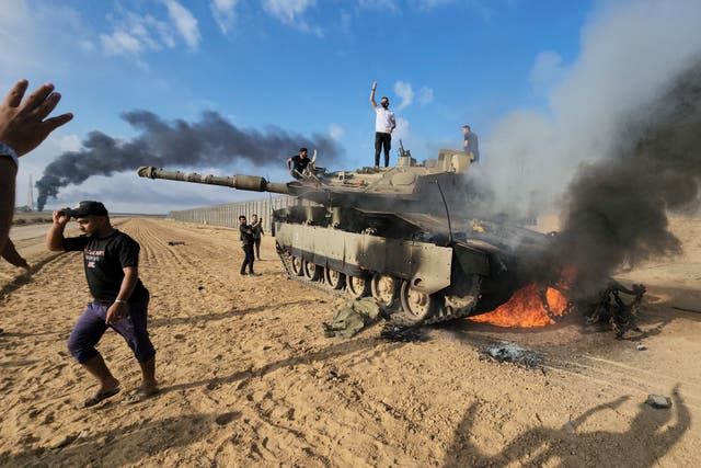 <p>Palestinians celebrate by a destroyed Israeli tank at the Gaza Strip fence east of Khan Younis</p>