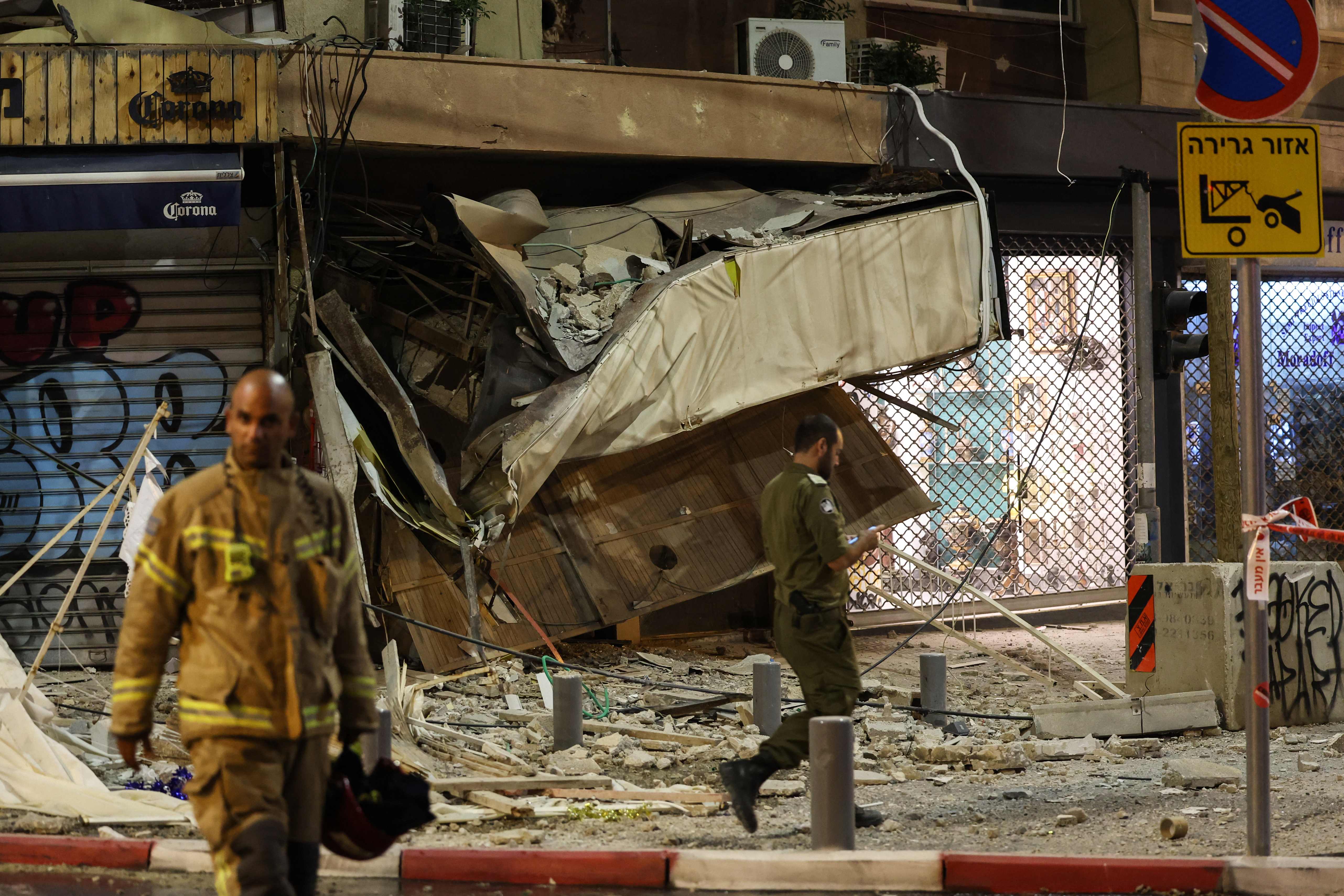 A rescuer walks in front of a damaged shop in Tel Aviv, after it was hit by a rocket fired by Palestinian militants from the Gaza Strip