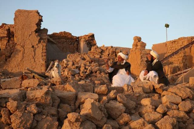 <p>Afghan residents sit at a damaged house after earthquake in Sarbuland village of Zendeh Jan, district of Herat province, on 7 October 2023</p>