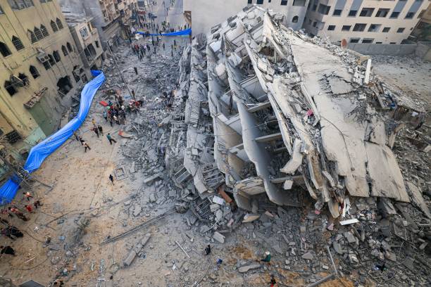 People inspect the ruins of a building destroyed in Israeli strikes in Gaza City on 8 October 2023
