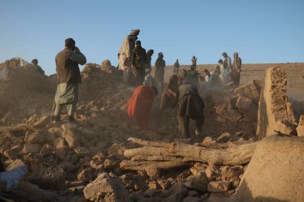 Afghan residents clear debris from a damaged house after an earthquake in Sarbuland village of Zendeh Jan district of Herat province on 7 October