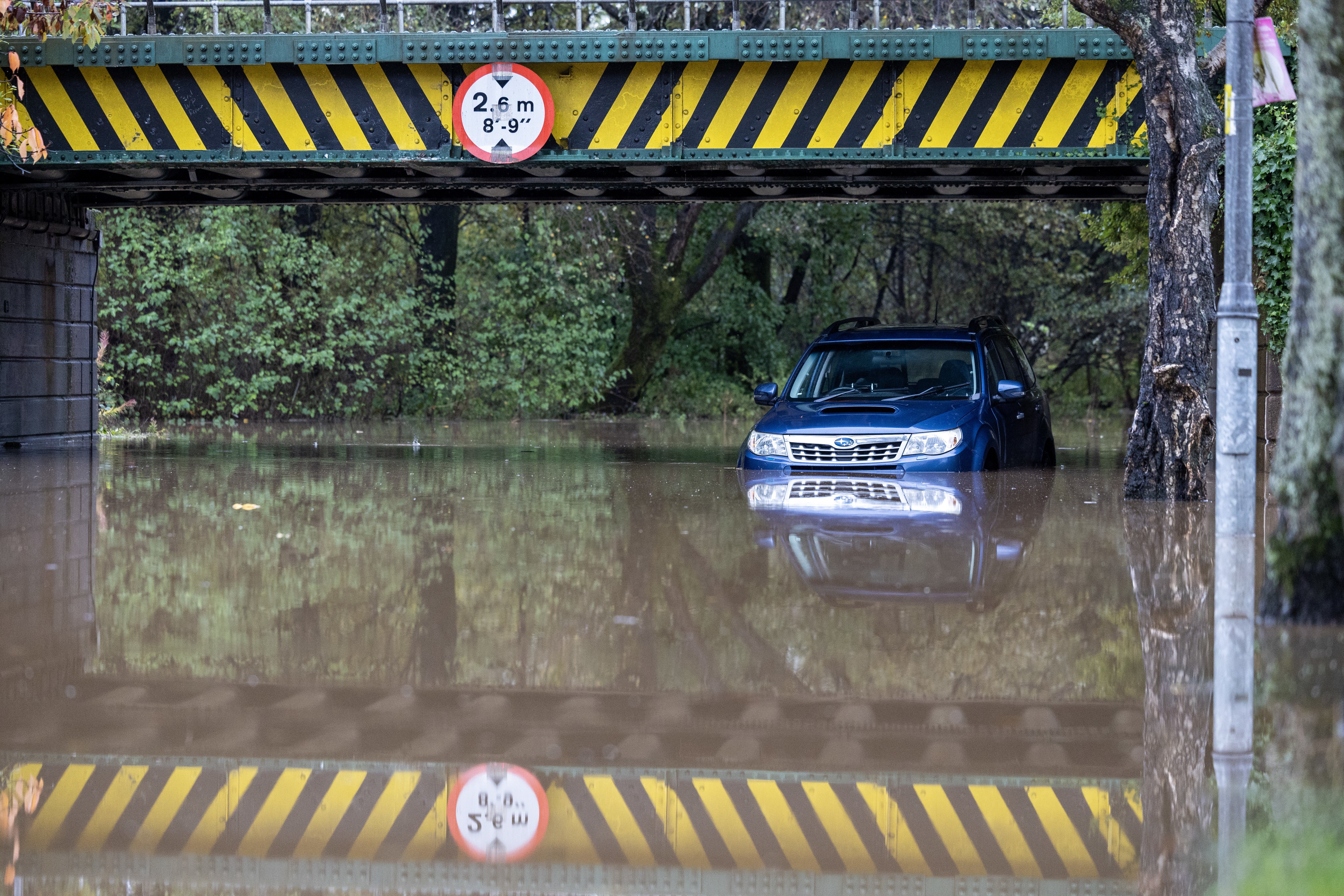 A car is left abandoned under a flooded railway bridge in West Dunbartonshire, as Scotland experiences extreme rainfall over the weekend, with 54 flood warnings issued
