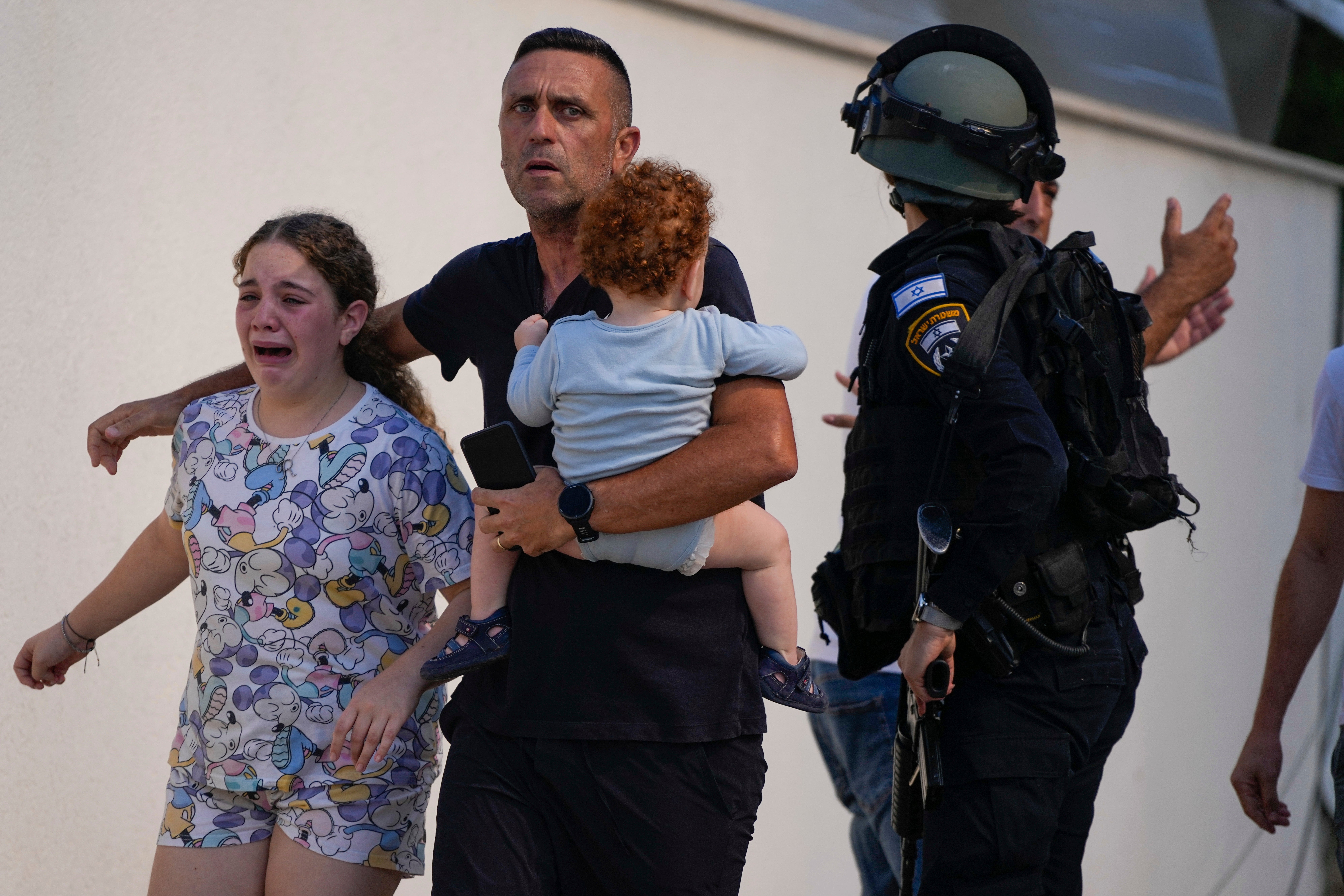 Israeli police officers evacuate a family from a site hit by a rocket fired from the Gaza Strip