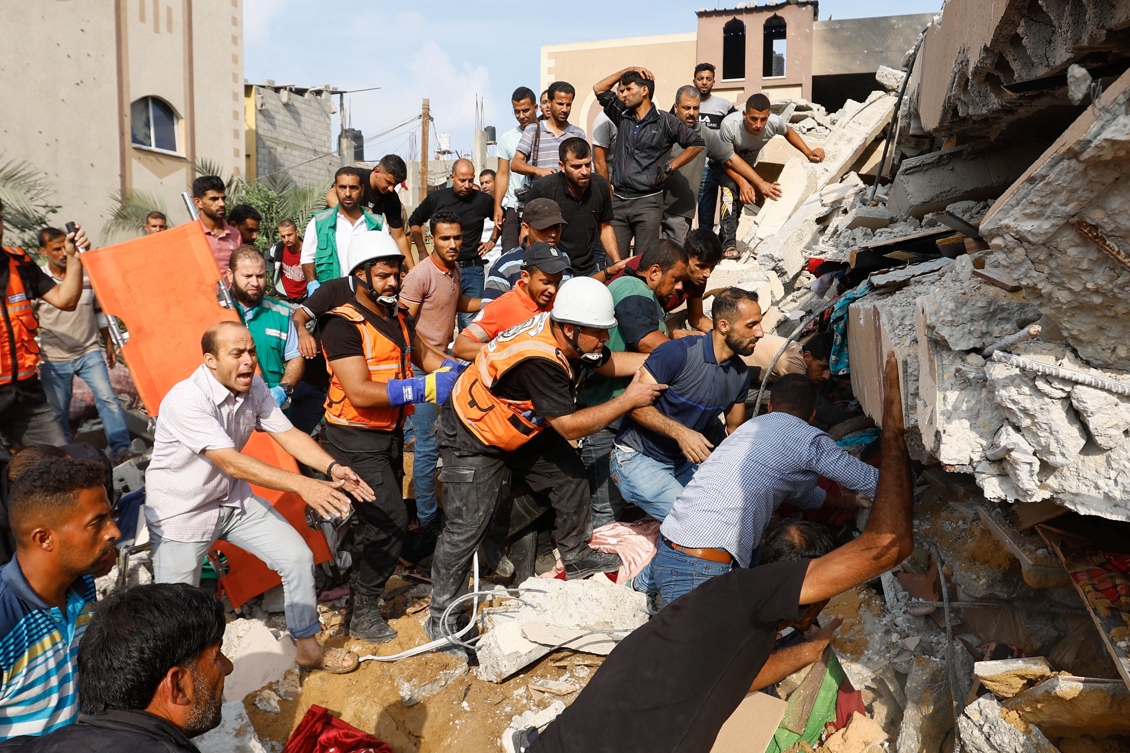 Palestinians search under the rubble of a house destroyed in Israeli strikes in Khan Younis