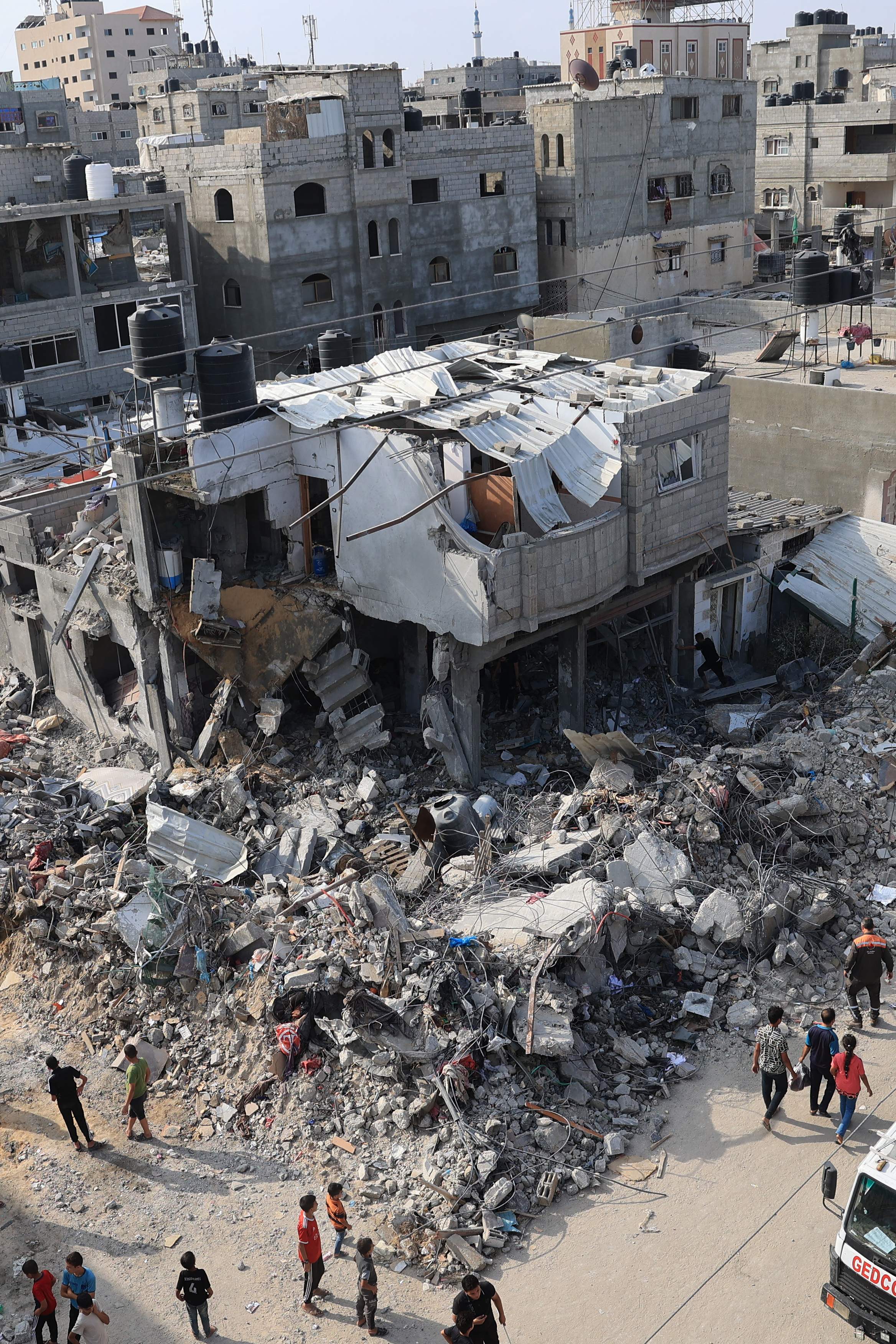 Palestinians gather round the rubble of buildings hit during Israeli airstrikes on Rafah in the southern Gaza Strip