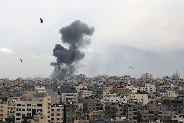 <p>A plume of smoke rises above buildings in Gaza City during an Israeli air strike</p>