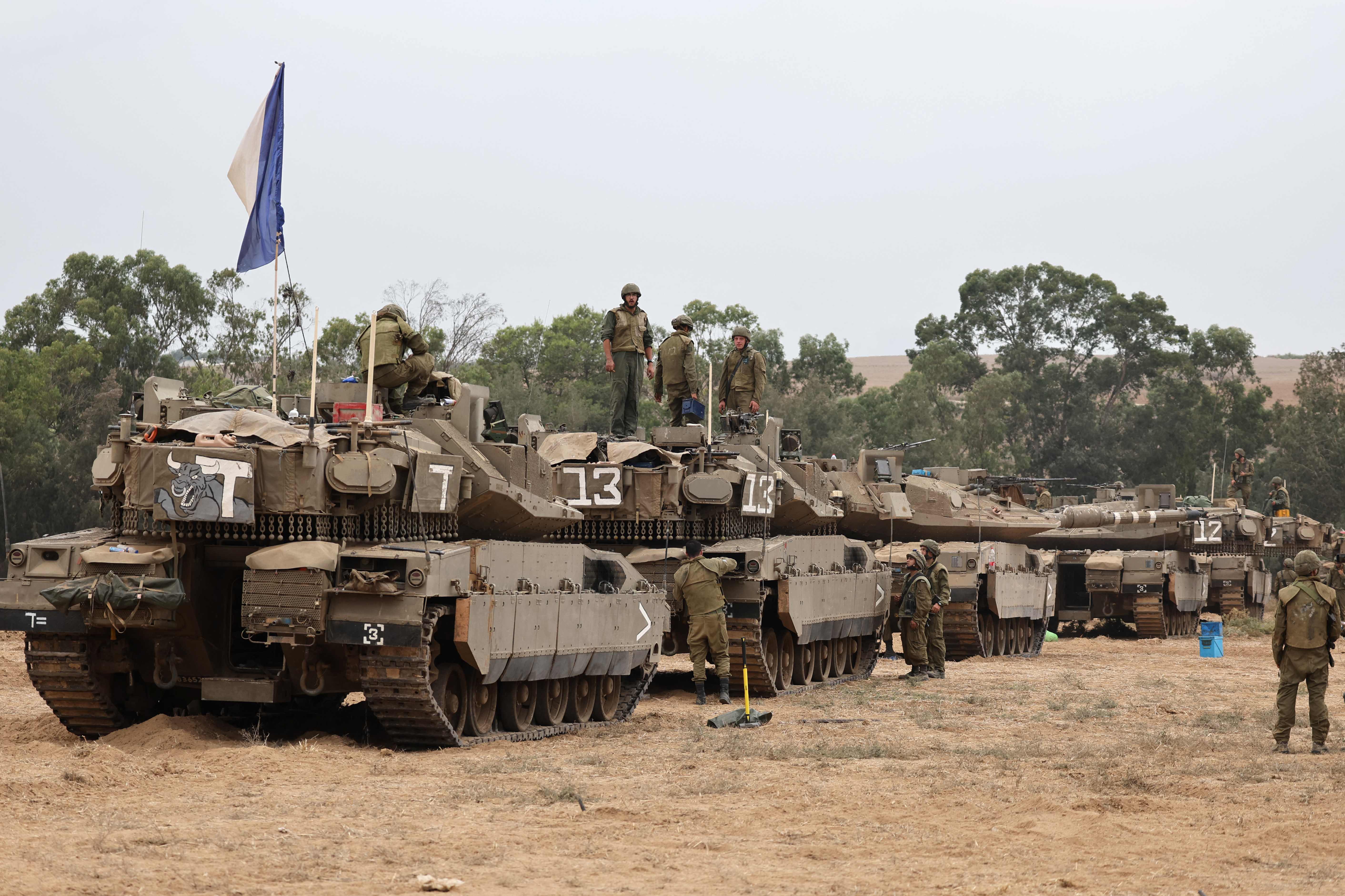 Israeli army soldiers are positioned with their Merkava tanks near the border with the Gaza Strip