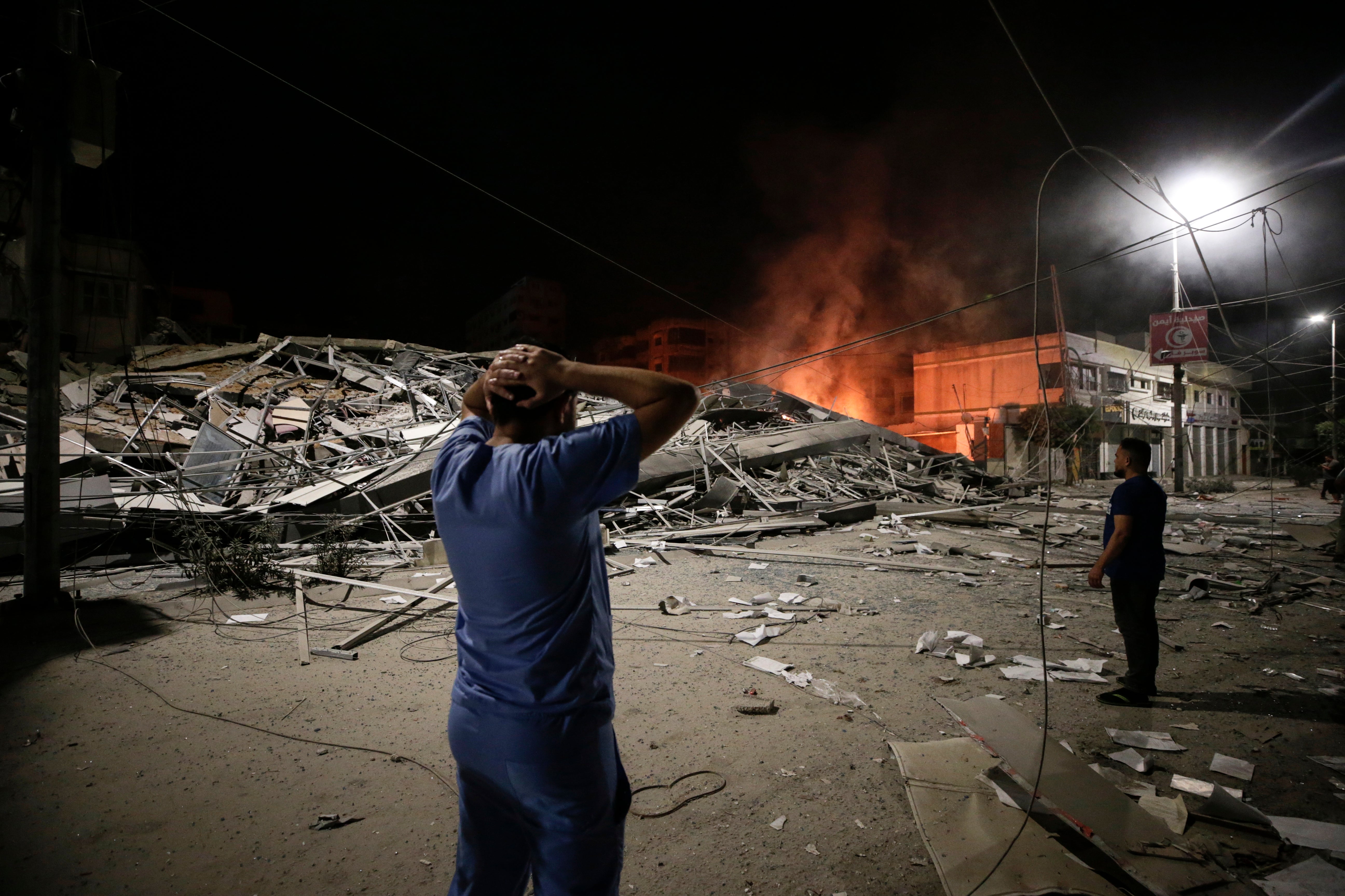 Palestinians look at the aftermath of an Israeli air strike on Gaza City