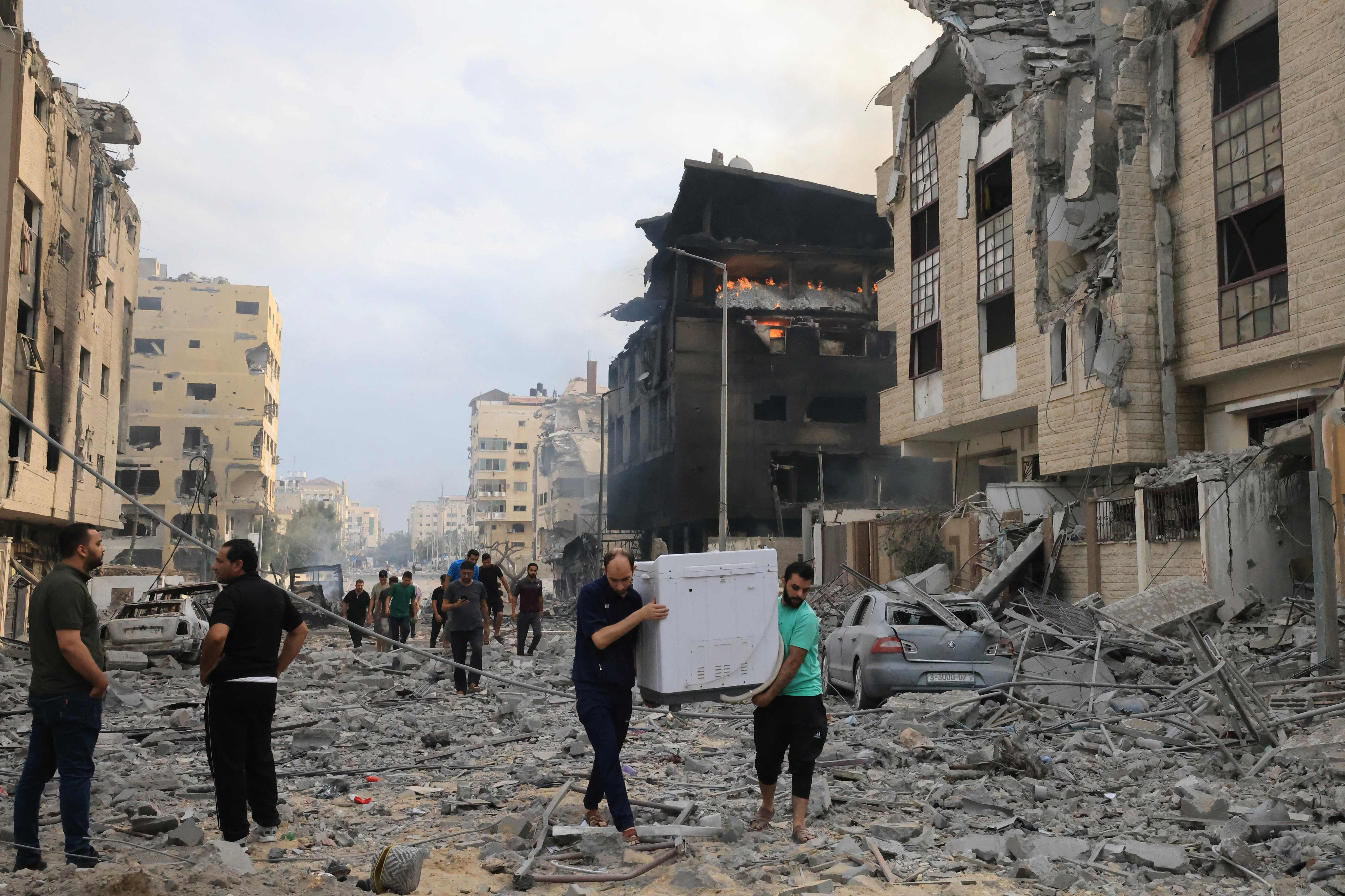 Palestinians slavage household items from damaged apartments following Israeli airstrikes on Gaza City