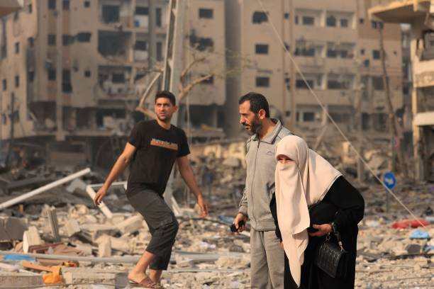 Palestinians walk through a ravaged neighbourhood as they move to safer areas, following Israeli airstrikes on Gaza City on Tuesday