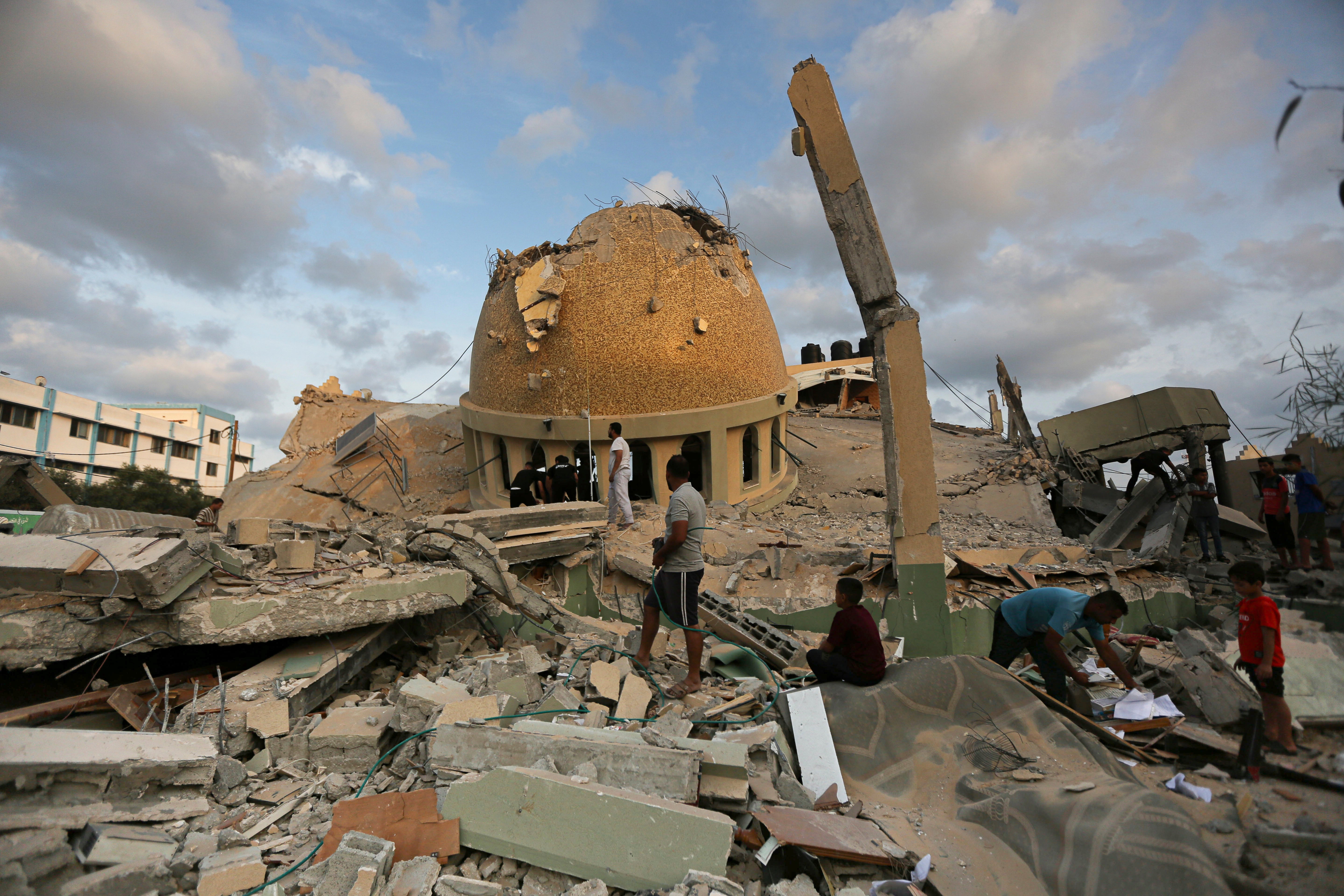 People stand outside a mosque destroyed in an Israeli air strike in Khan Younis, Gaza Strip on Sunday