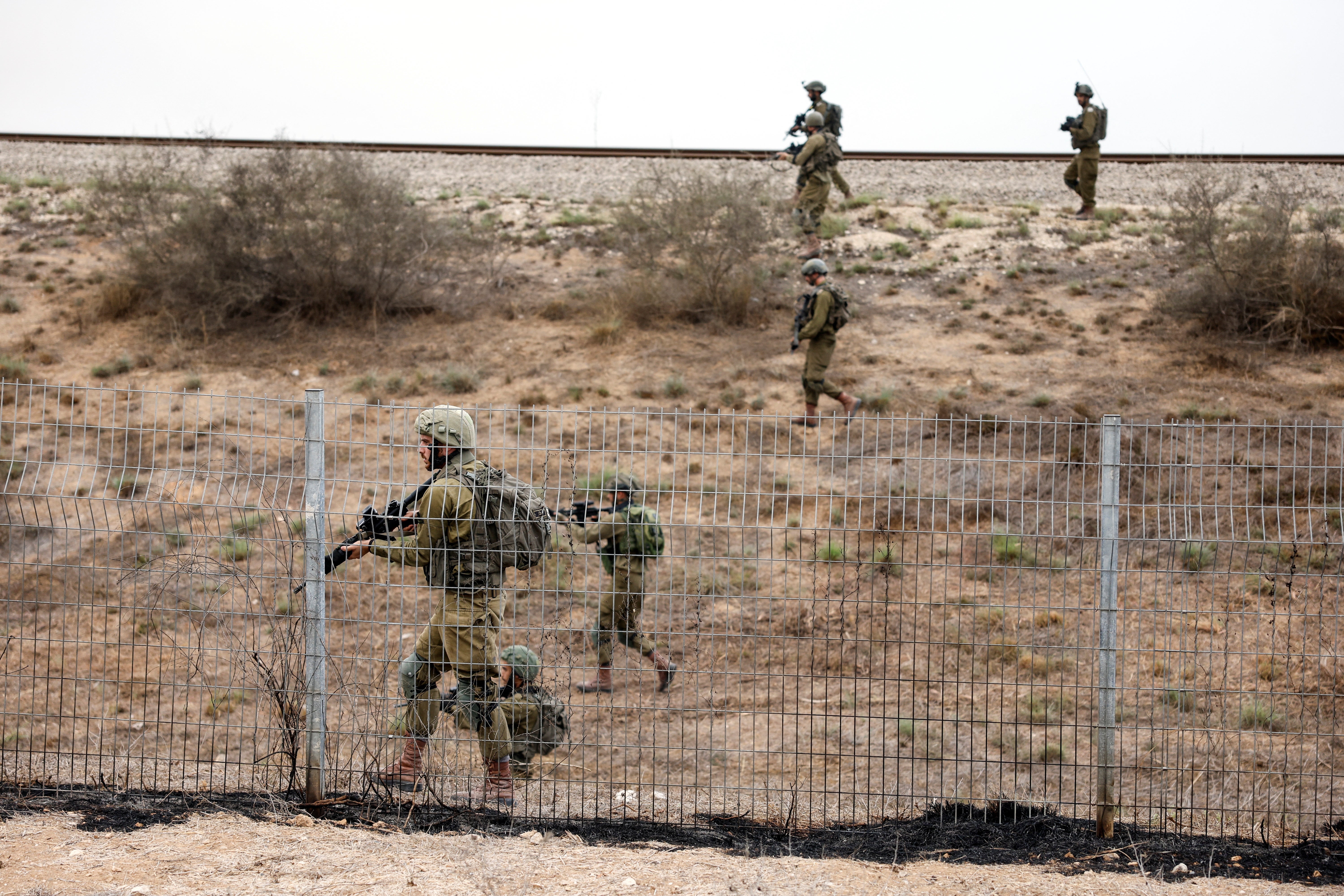 Israeli soldiers scan an area while sirens sound as rockets from Gaza are launched towards Israel