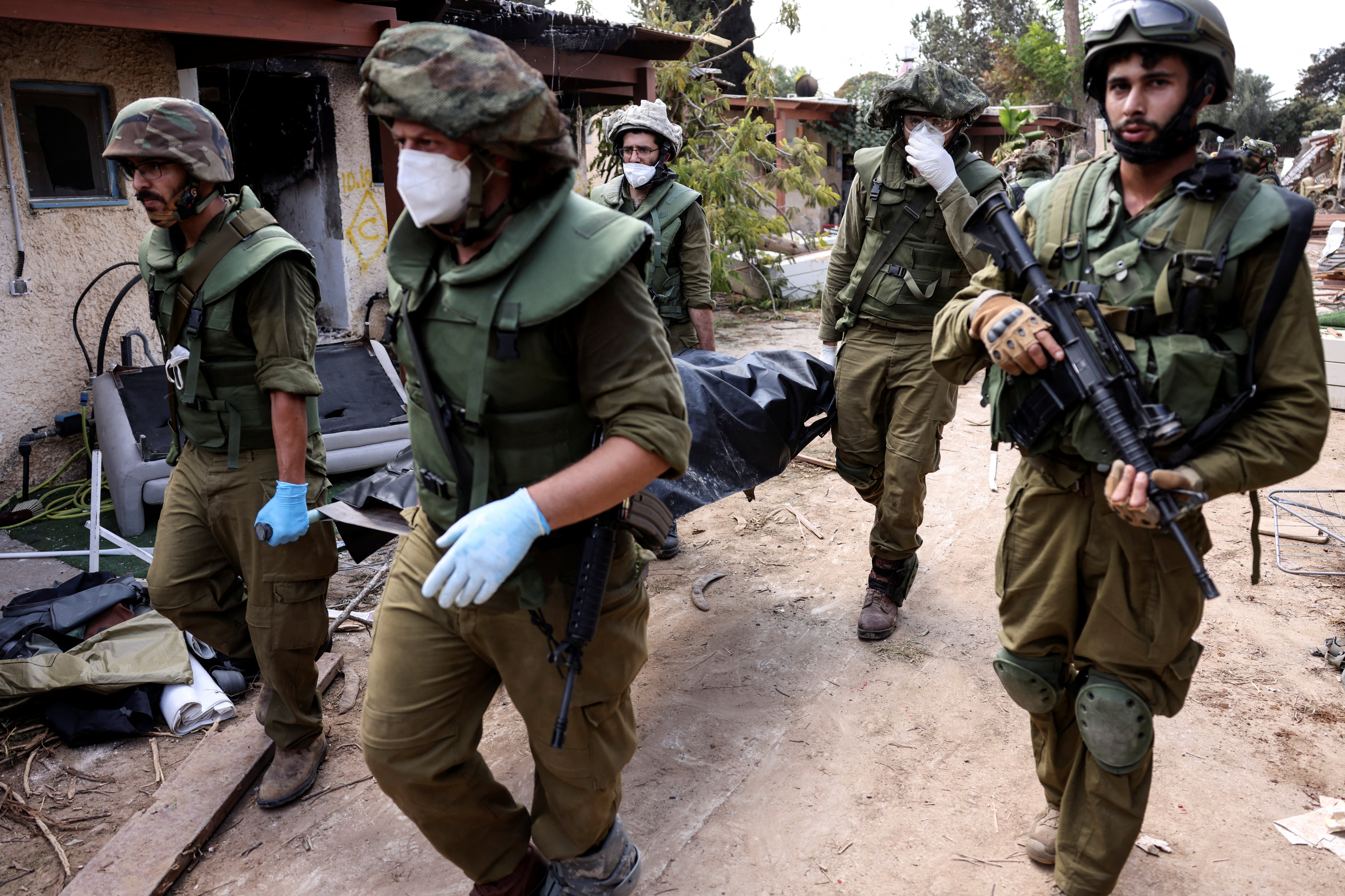 Israeli soldiers carry a body in Kfar Aza