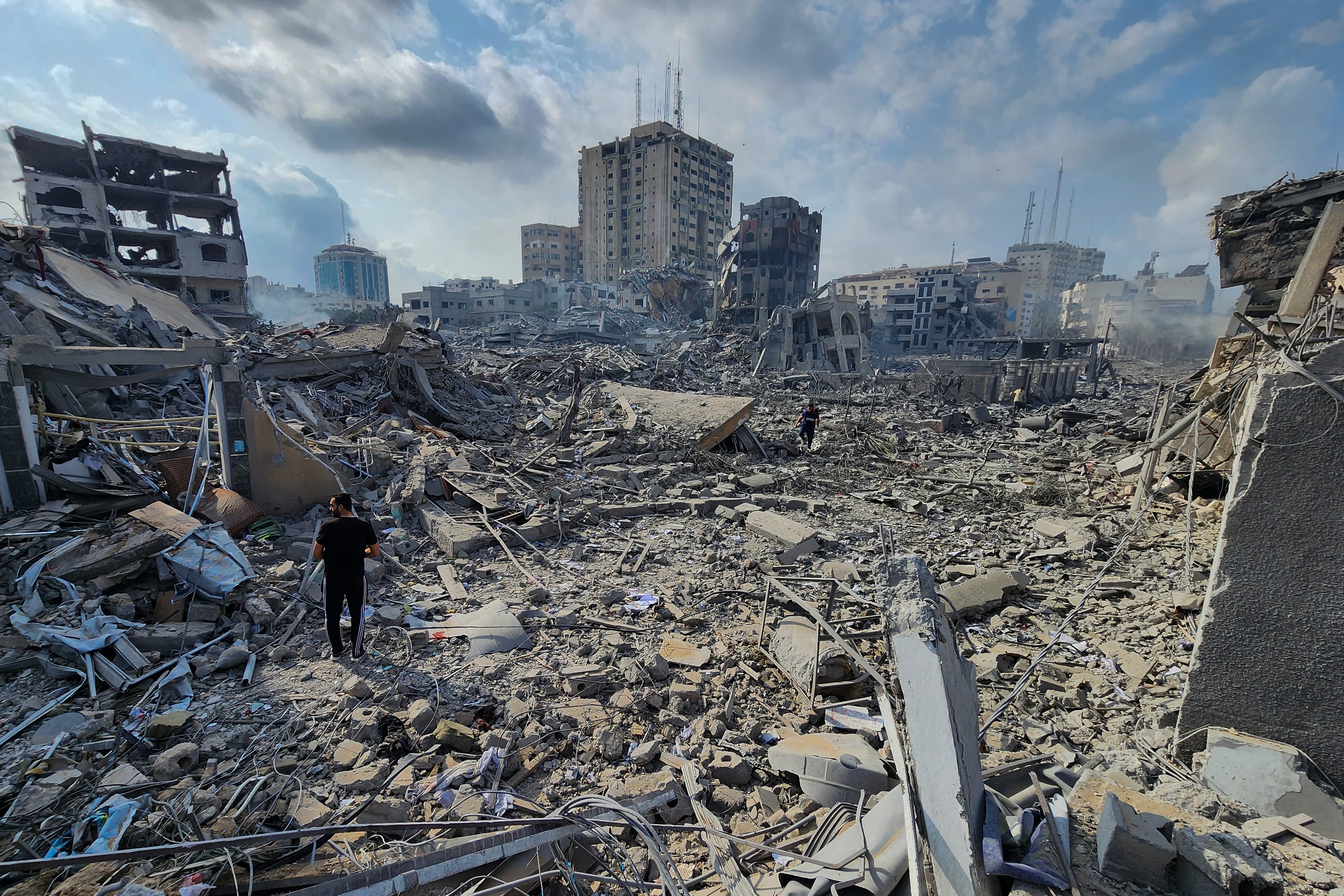 Palestinians walk through the rubble of buildings destroyed by Israeli airstrikes in Gaza City on Tuesday, Oct. 10, 2023.