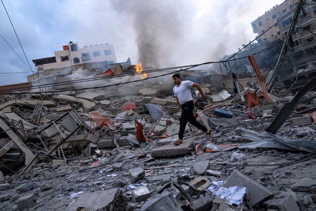<p>Palestinians walk amid the rubble following Israeli airstrikes in Gaza City </p>