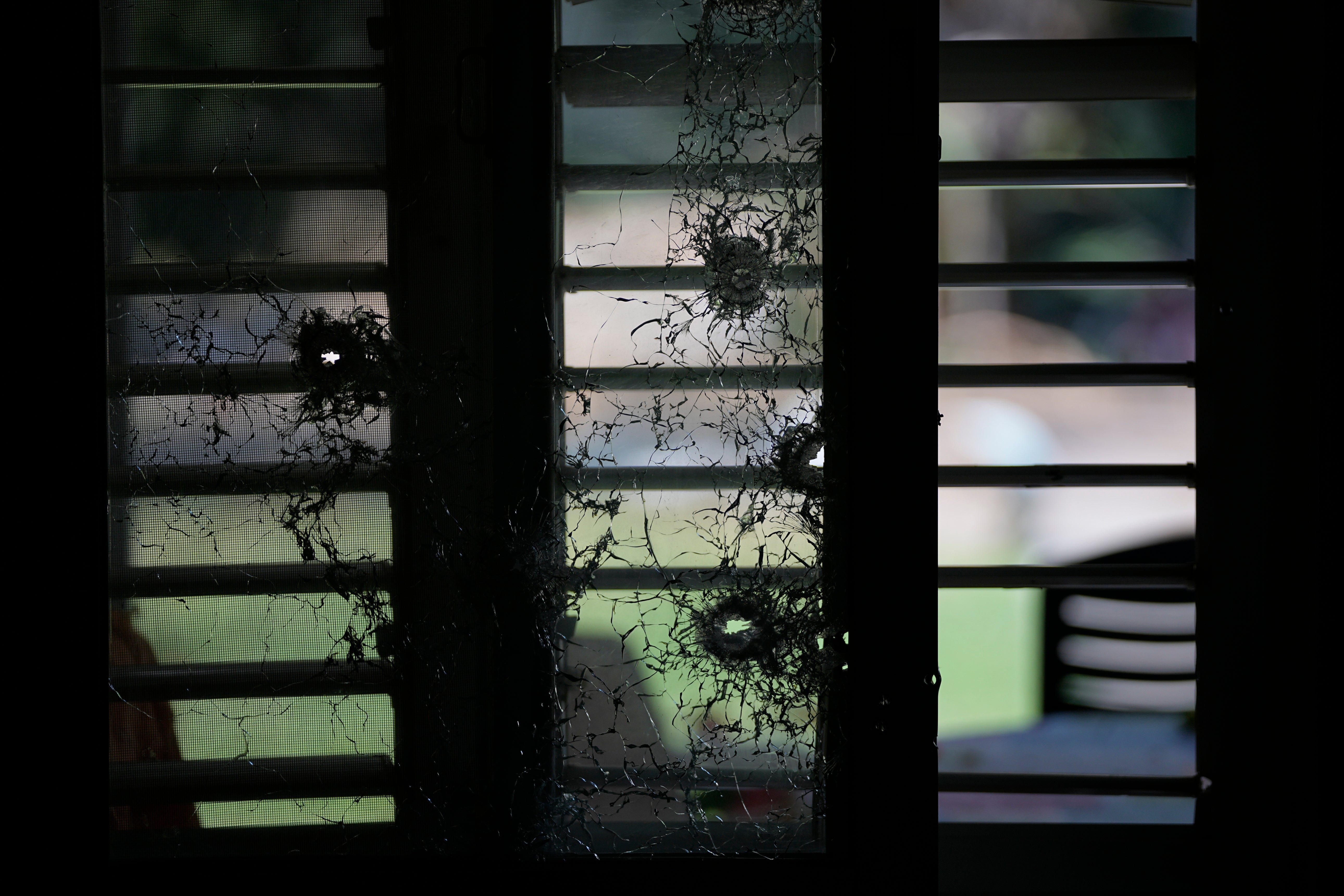 A window pierced by bullets is seen from inside a house in kibbutz Kfar Aza
