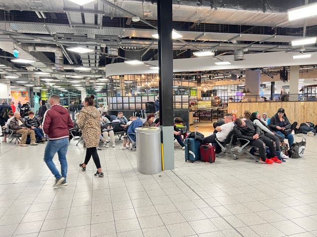 <p>Passengers wait at Luton Airport after flights cancelled until Wednesday noon following fire at the car park</p>