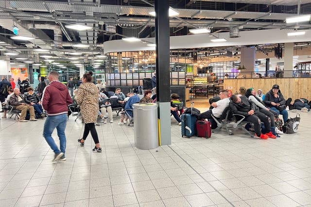<p>Passengers wait at Luton Airport after flights cancelled until Wednesday noon following fire at the car park</p>