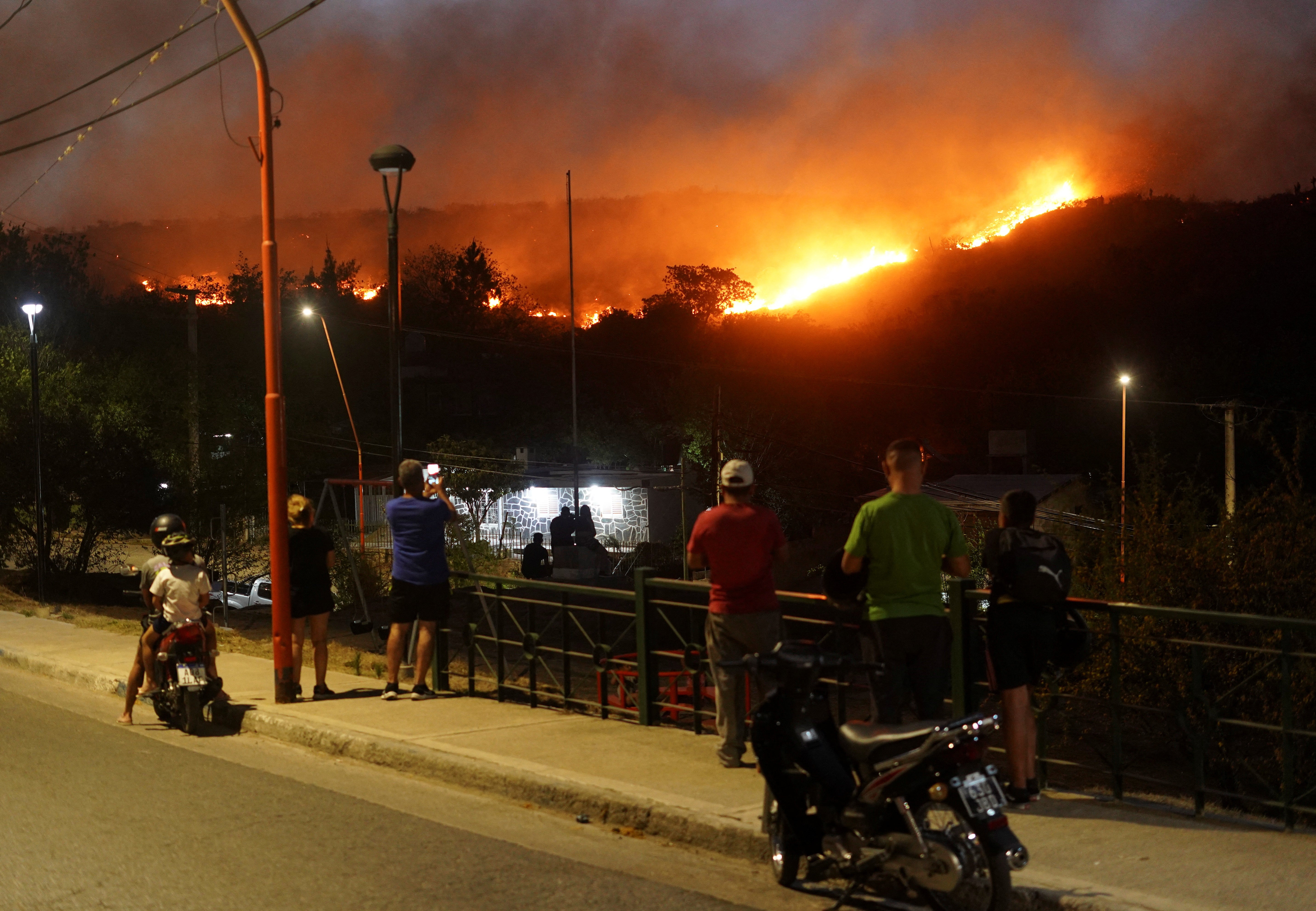 People look at a wildfire that has forced the evacuation of residents