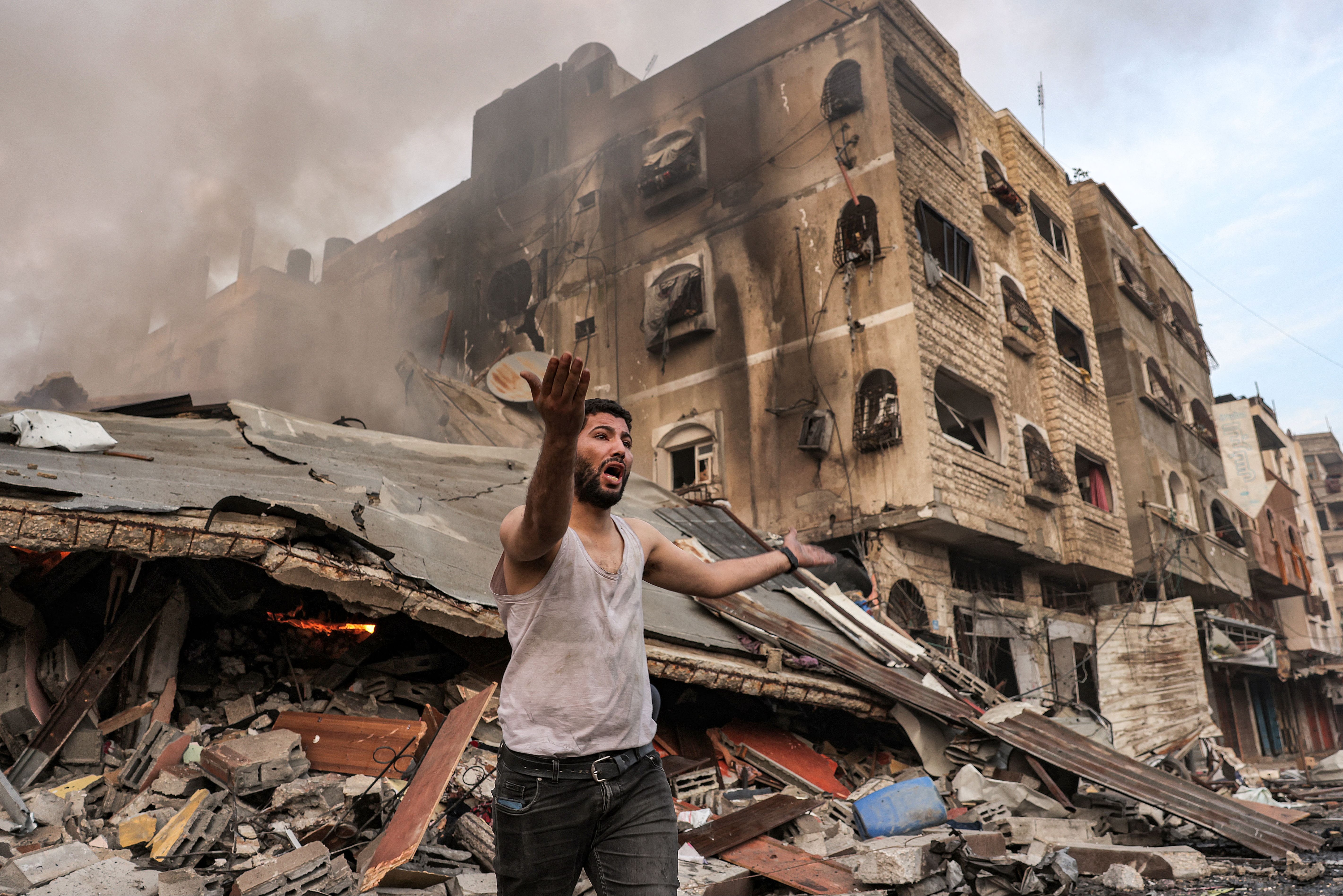 A man reacts outside a burning collapsed building following Israeli bombardment in Gaza City on October 11