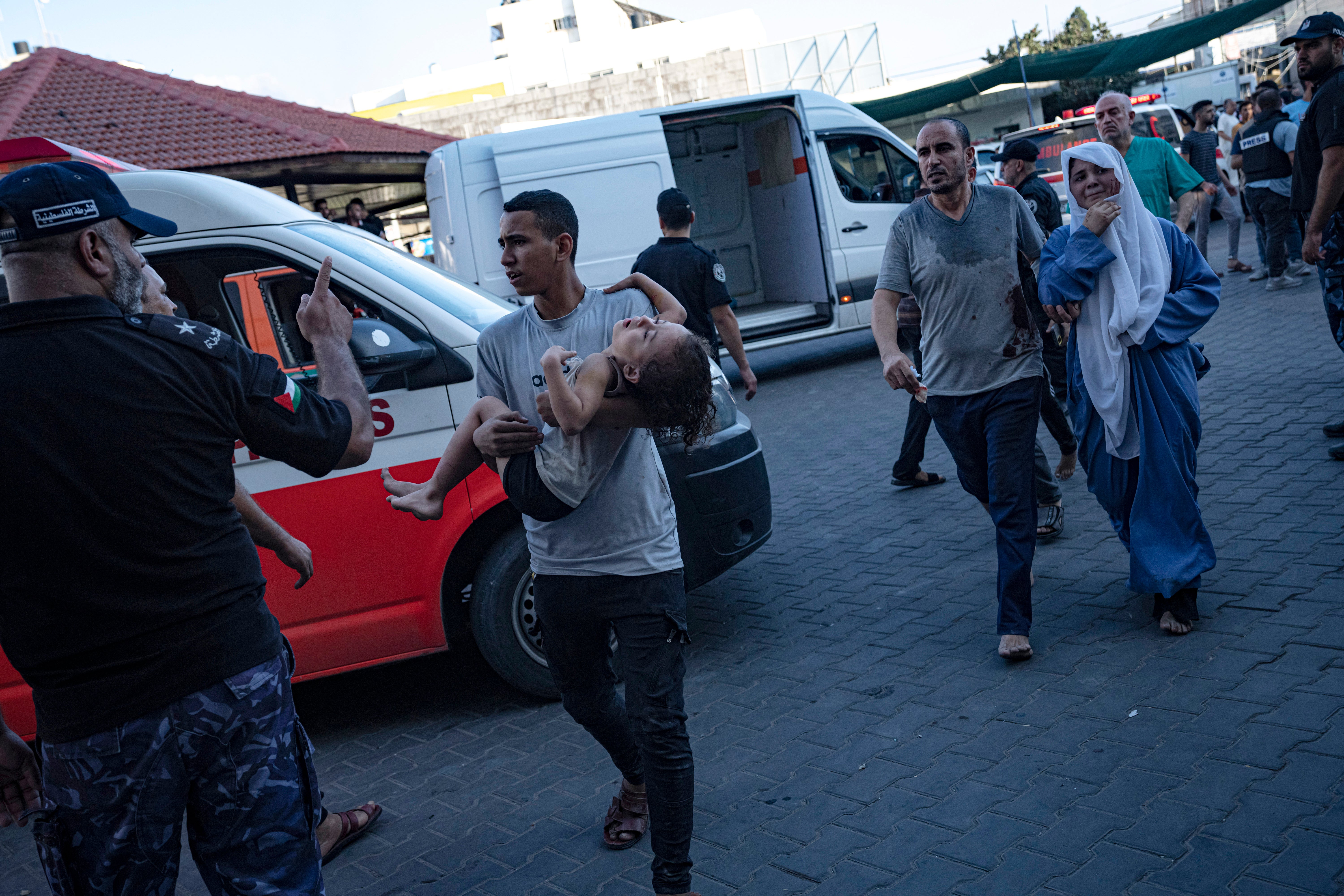 A Palestinian man carries a wounded girl into Shifa Hospital as Israel pummels Gaza
