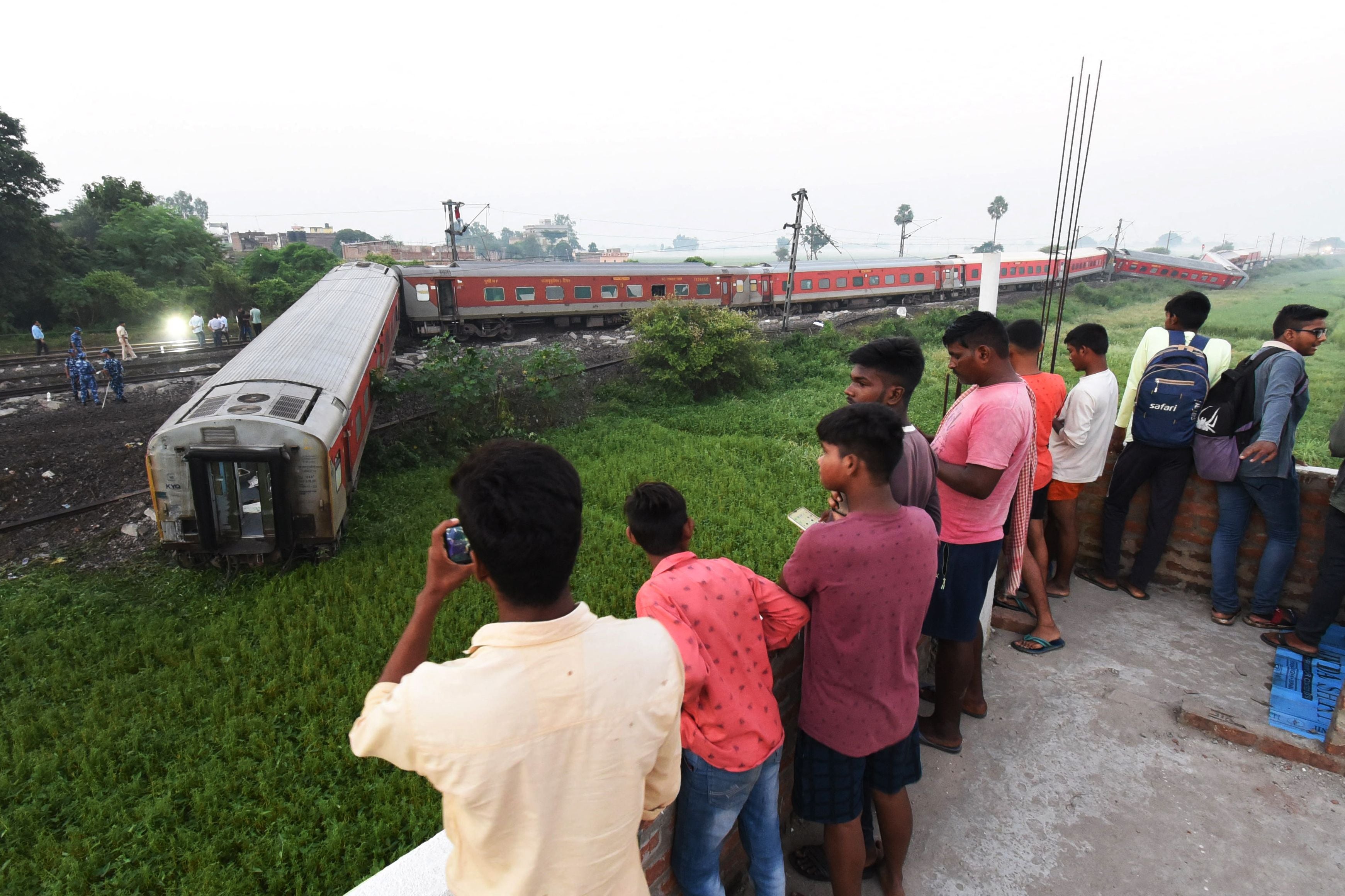 People watch damaged carriages near Raghunathpur railway station some 44km from Buxar on 11 October