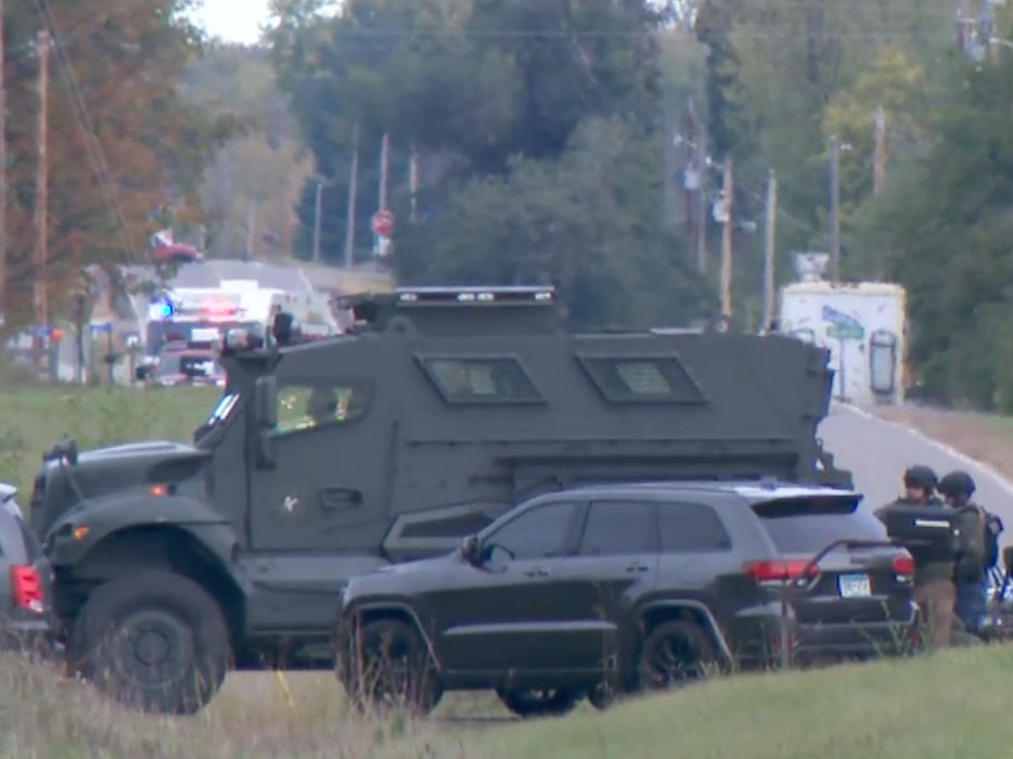 A heavy police response vehicle and officers in tactical gear wait near a Princeton, Minnesota property where five law enforcement officers were shot