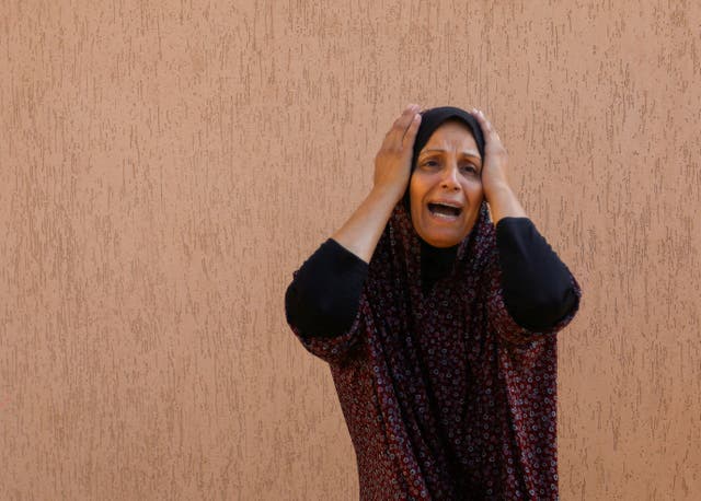 <p>A Palestinian woman reacts in the aftermath of Israeli strikes</p>