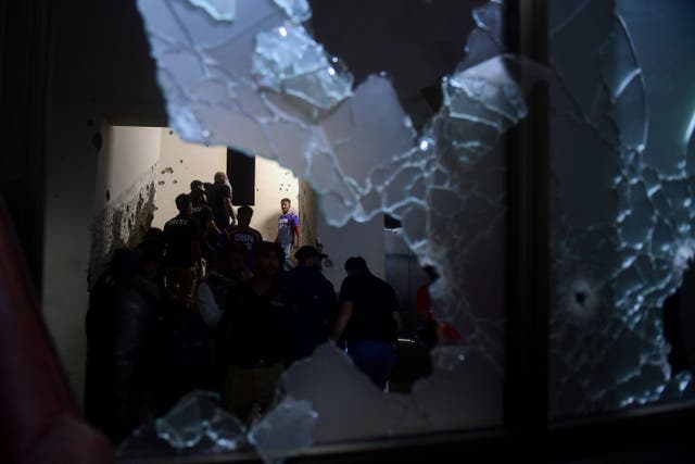 <p>Security personnel and volunteers are seen through a shattered window as they inspect a police compound after taking control of the building, following an attack by Pakistani Taliban fighters, in Karachi on 17 February 2023</p>